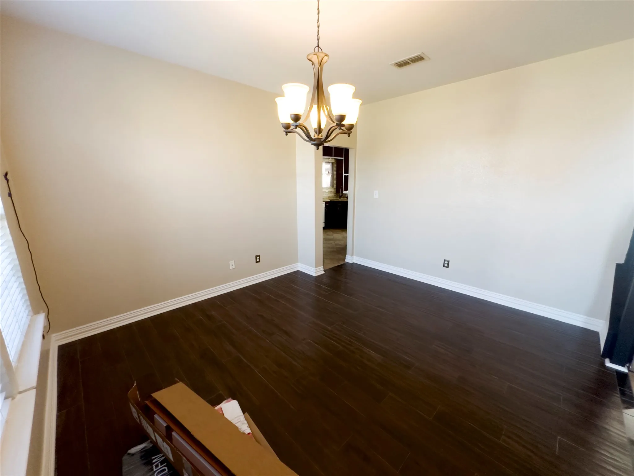 Unfurnished dining area with dark wood-type flooring and a chandelier