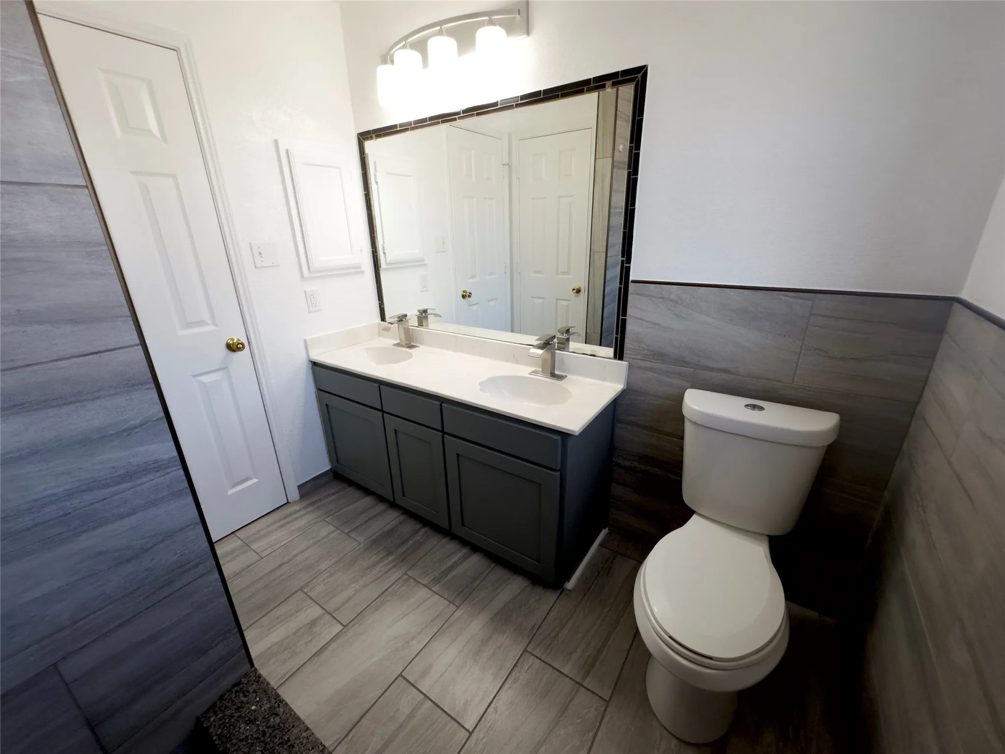 Bathroom featuring double vanity, tile walls, and wood tiled floors
