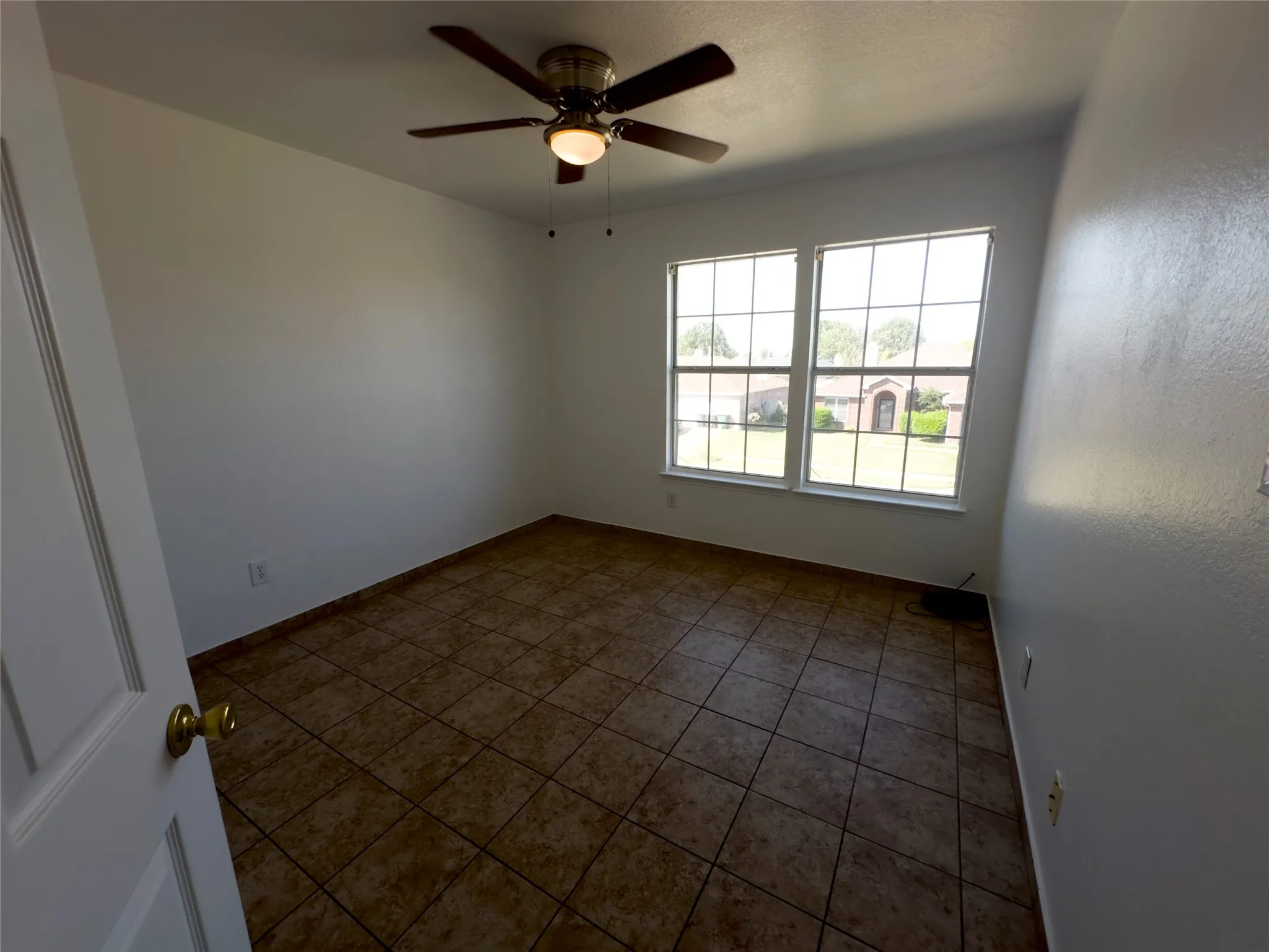 Spare room featuring tile patterned floors and ceiling fan