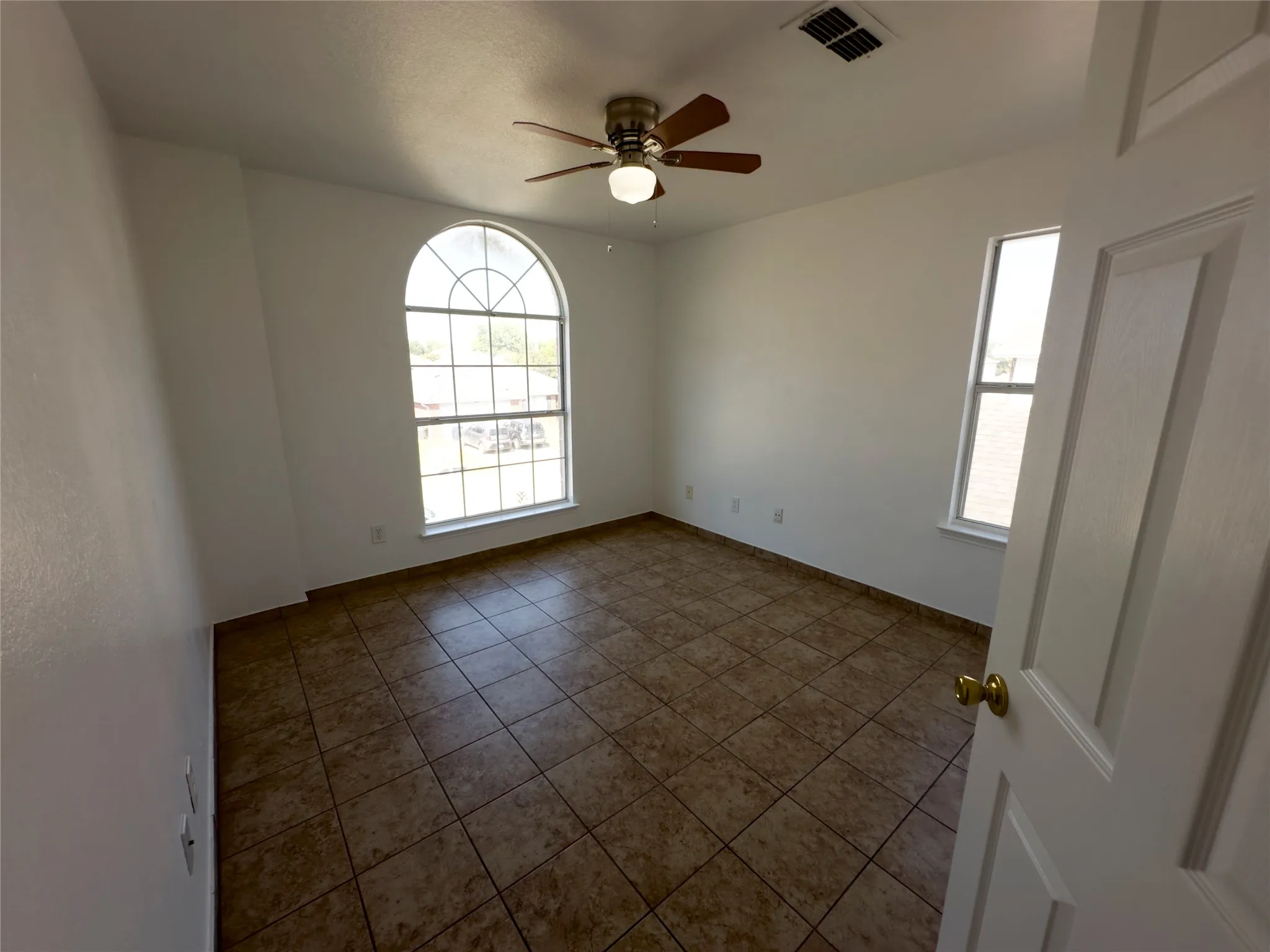 Empty room with a ceiling fan and tile patterned flooring