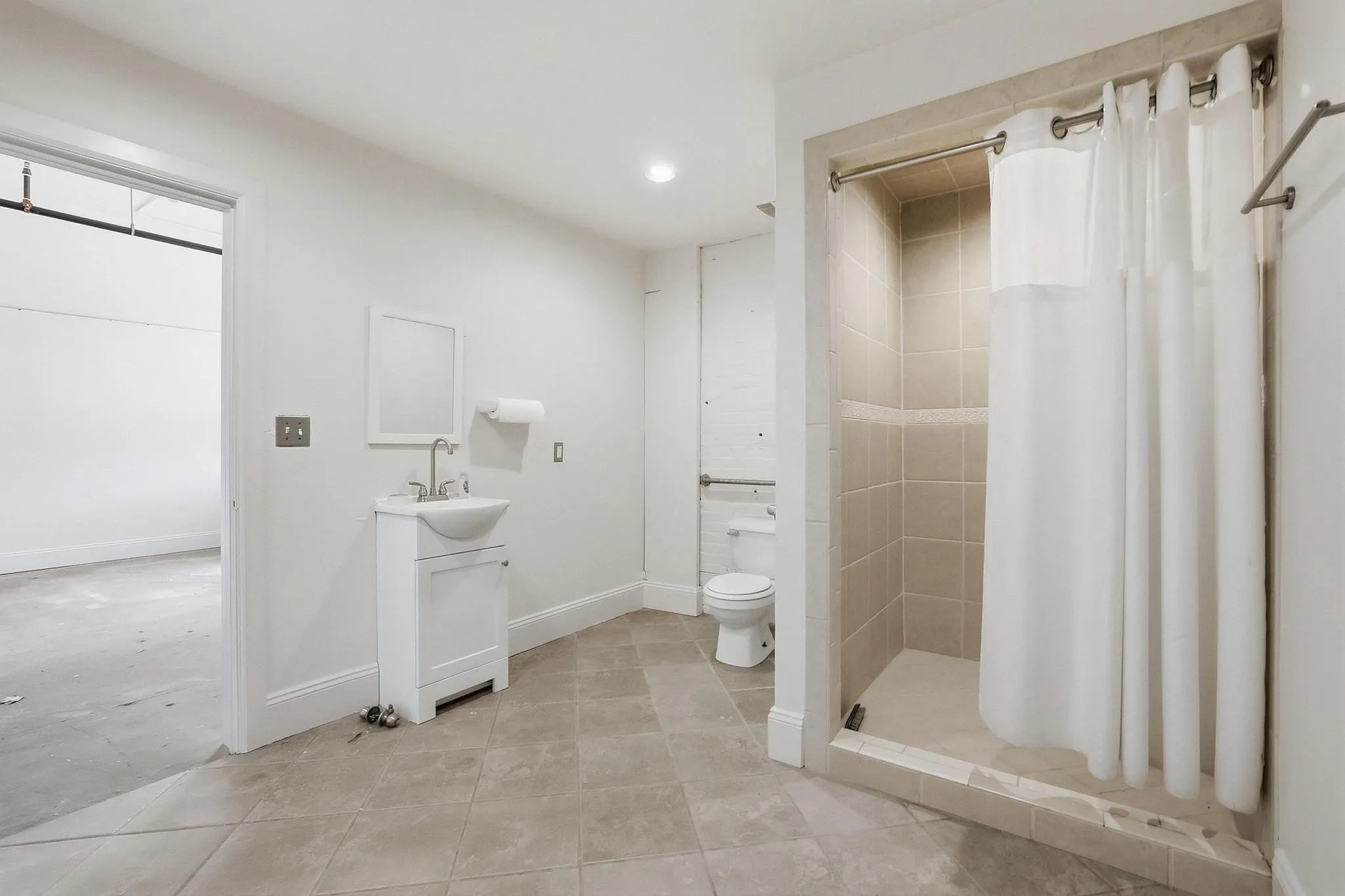 Tiled flooring throughout, pedestal sink with vanity, fully tiled shower enclosure, and recessed lighting