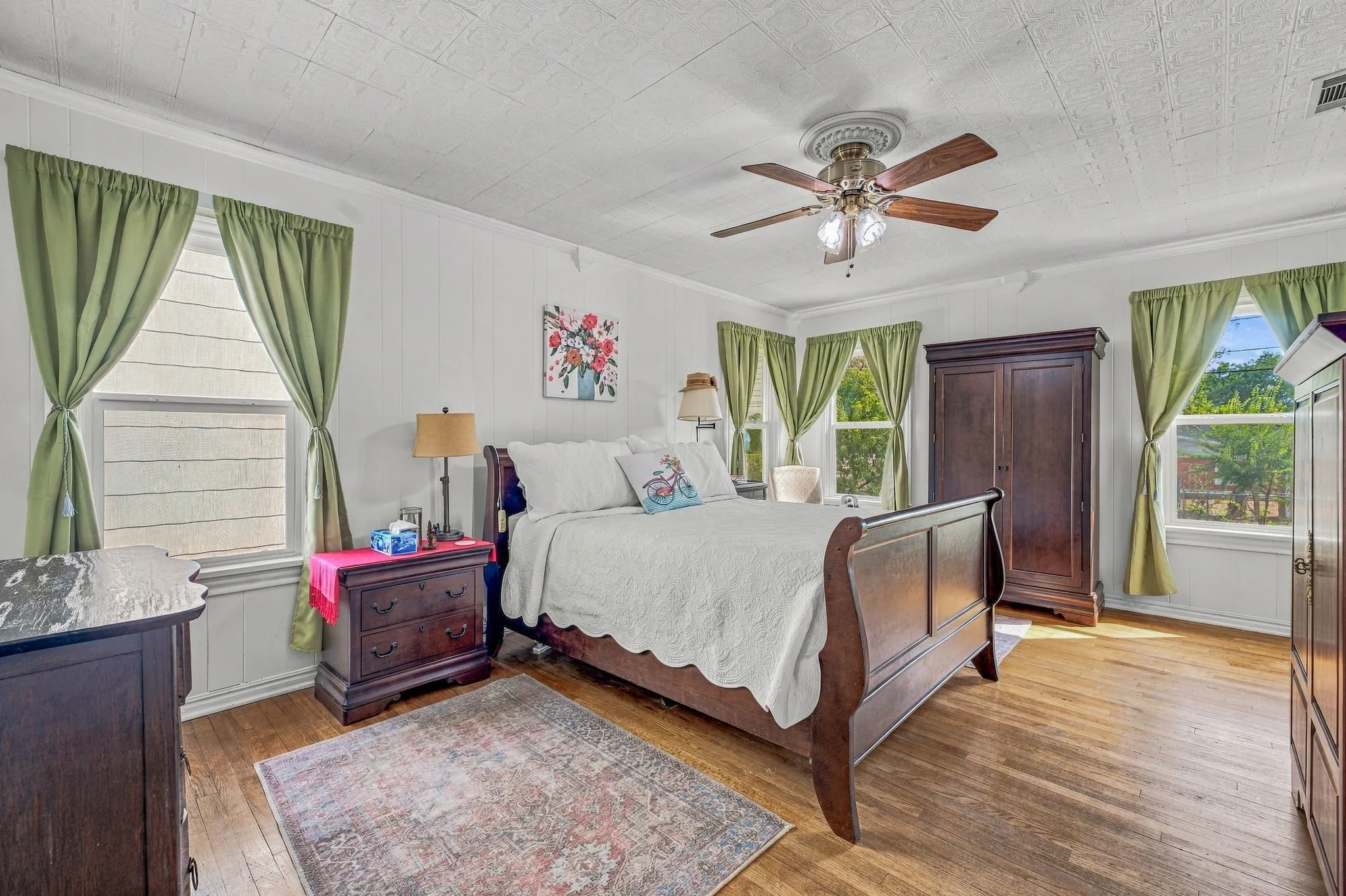 Large primary bedroom with multiple windows to let in ample natural light. Original hardwood flooring and two closets.