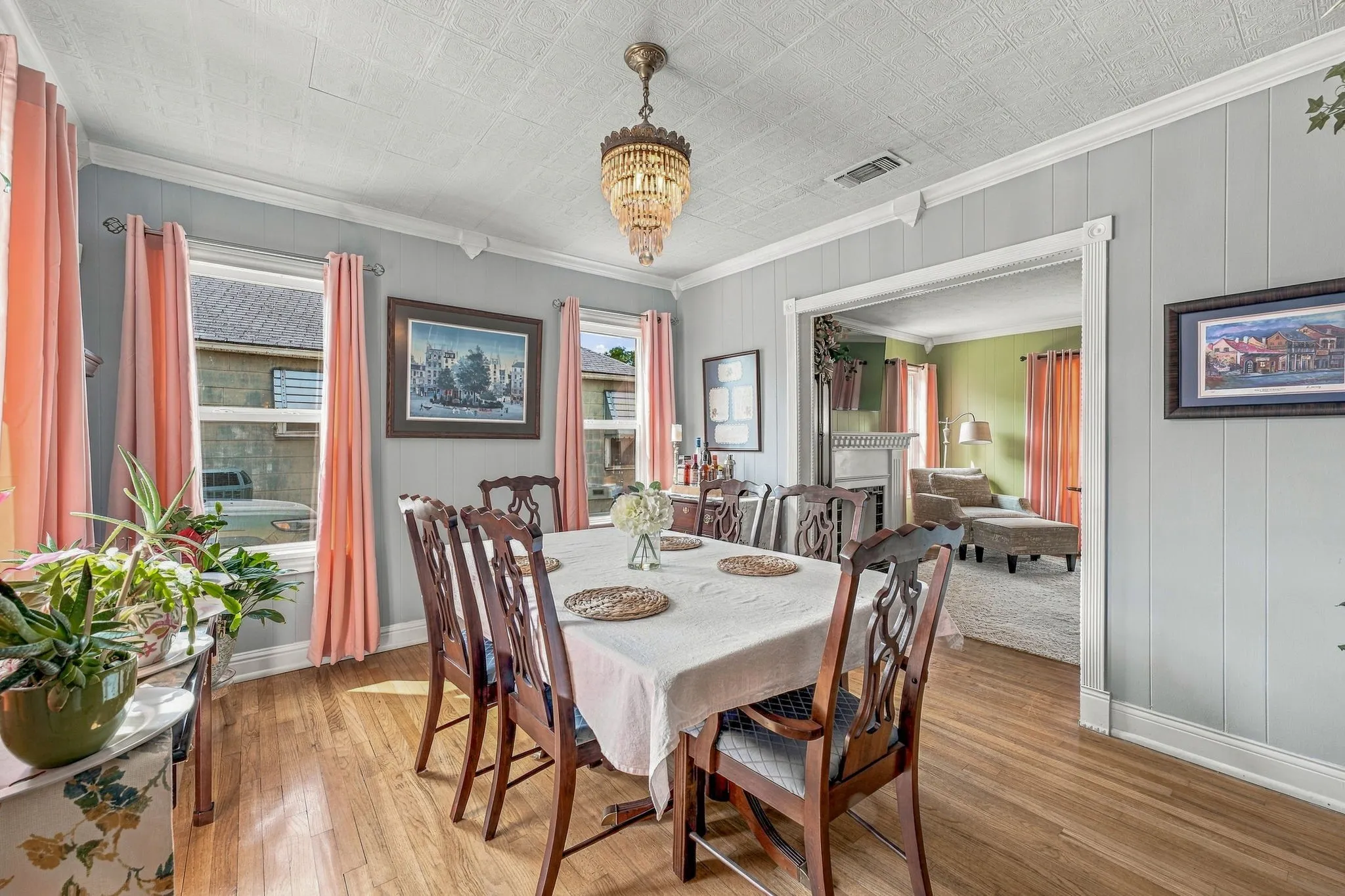 Dining room filled with natural light and origianl hardwood flooring and decorative chandelier.