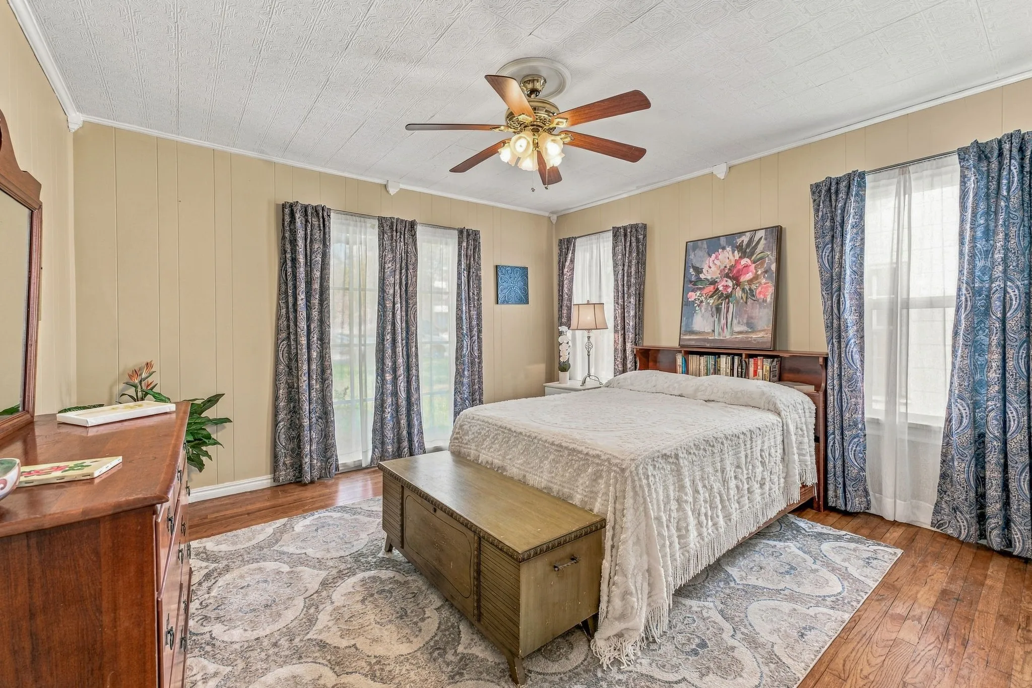 Second bedroom with multiple windows and original hardwood floors.