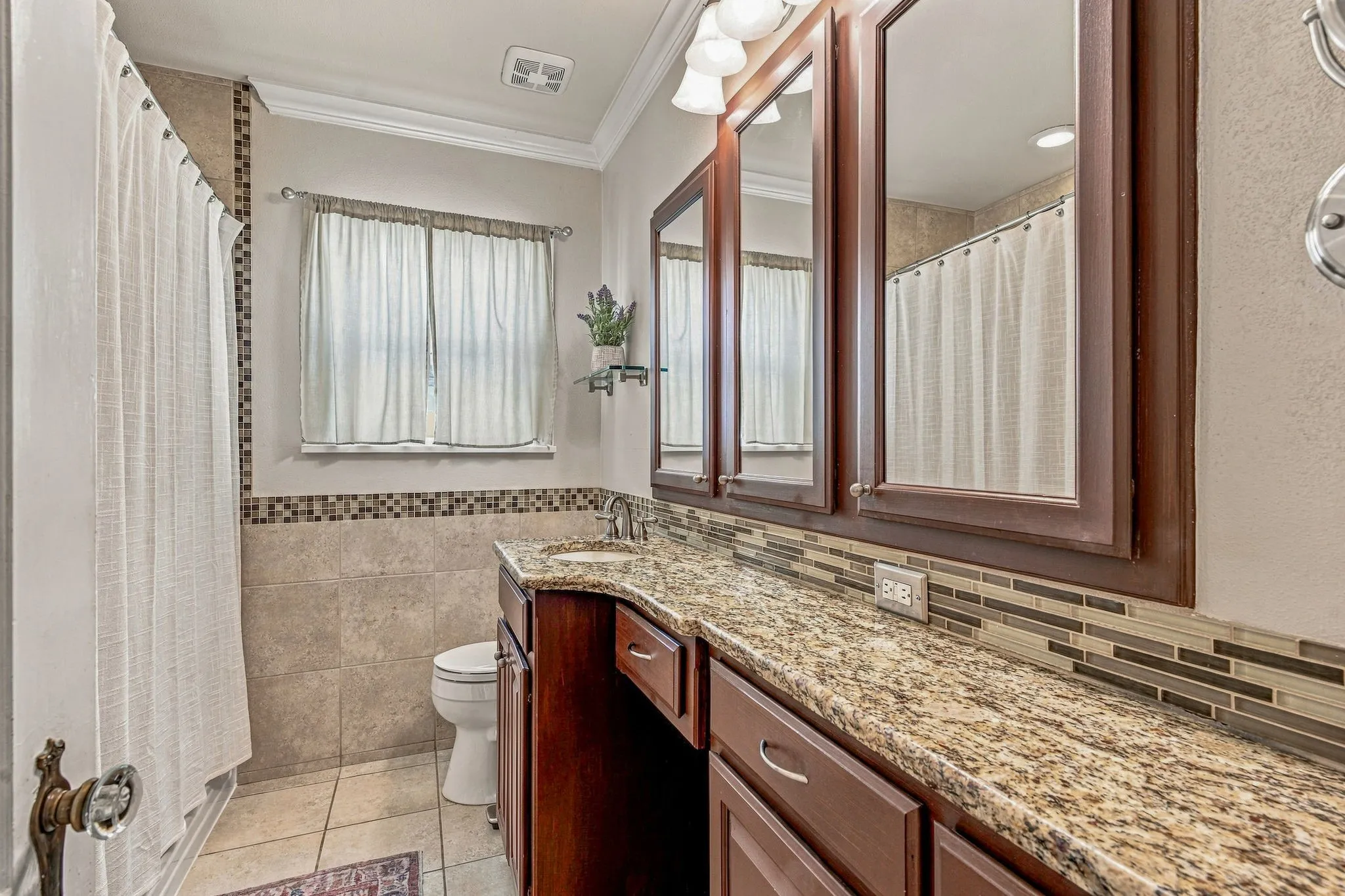 Updated bathroom with granite counters and ample storage.