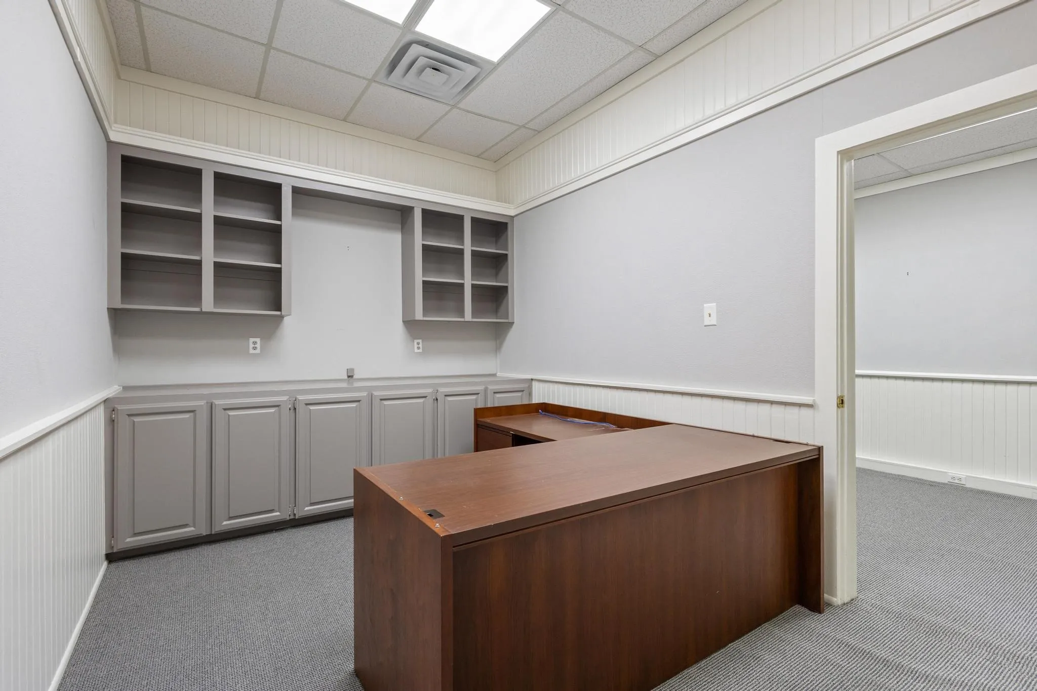 Built-in cabinetry with shelving, beadboard wainscoting, and a drop ceiling with recessed lighting