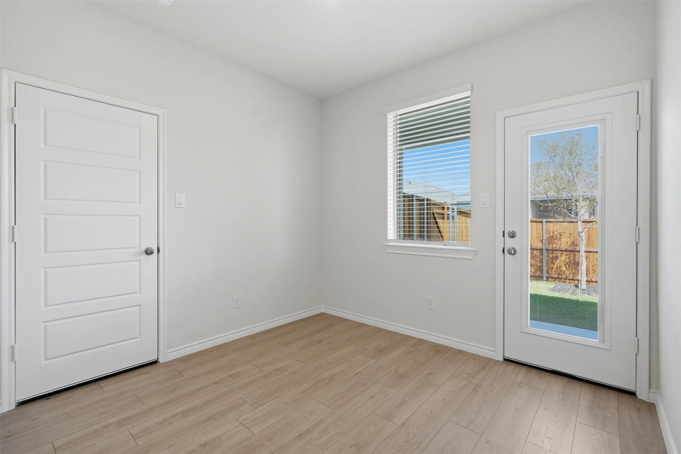 Wood-finish flooring, white walls, and a multi-paneled door