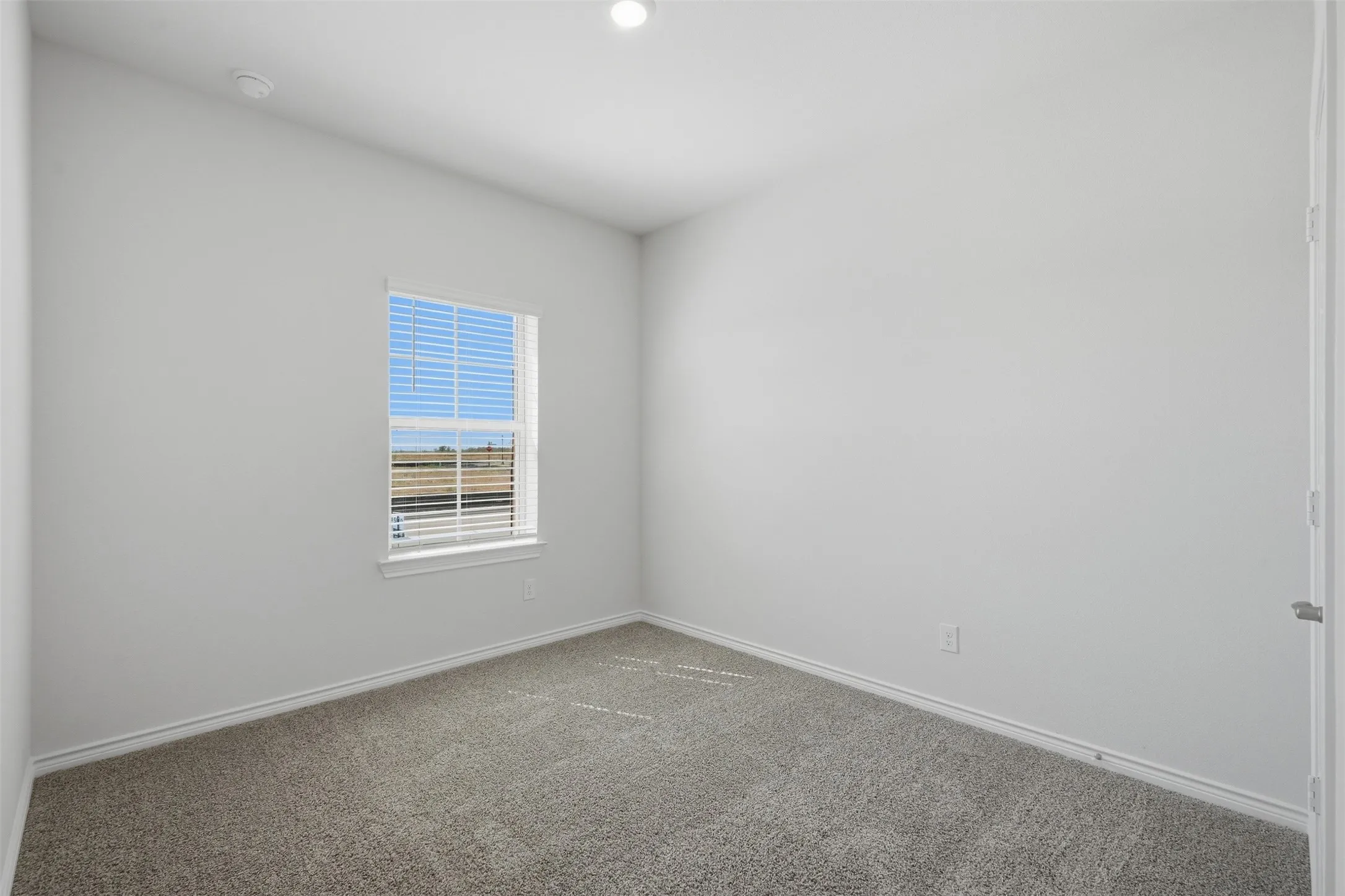 Neutral wall paint, gray carpet flooring, window with blinds, recessed ceiling light, and white trim