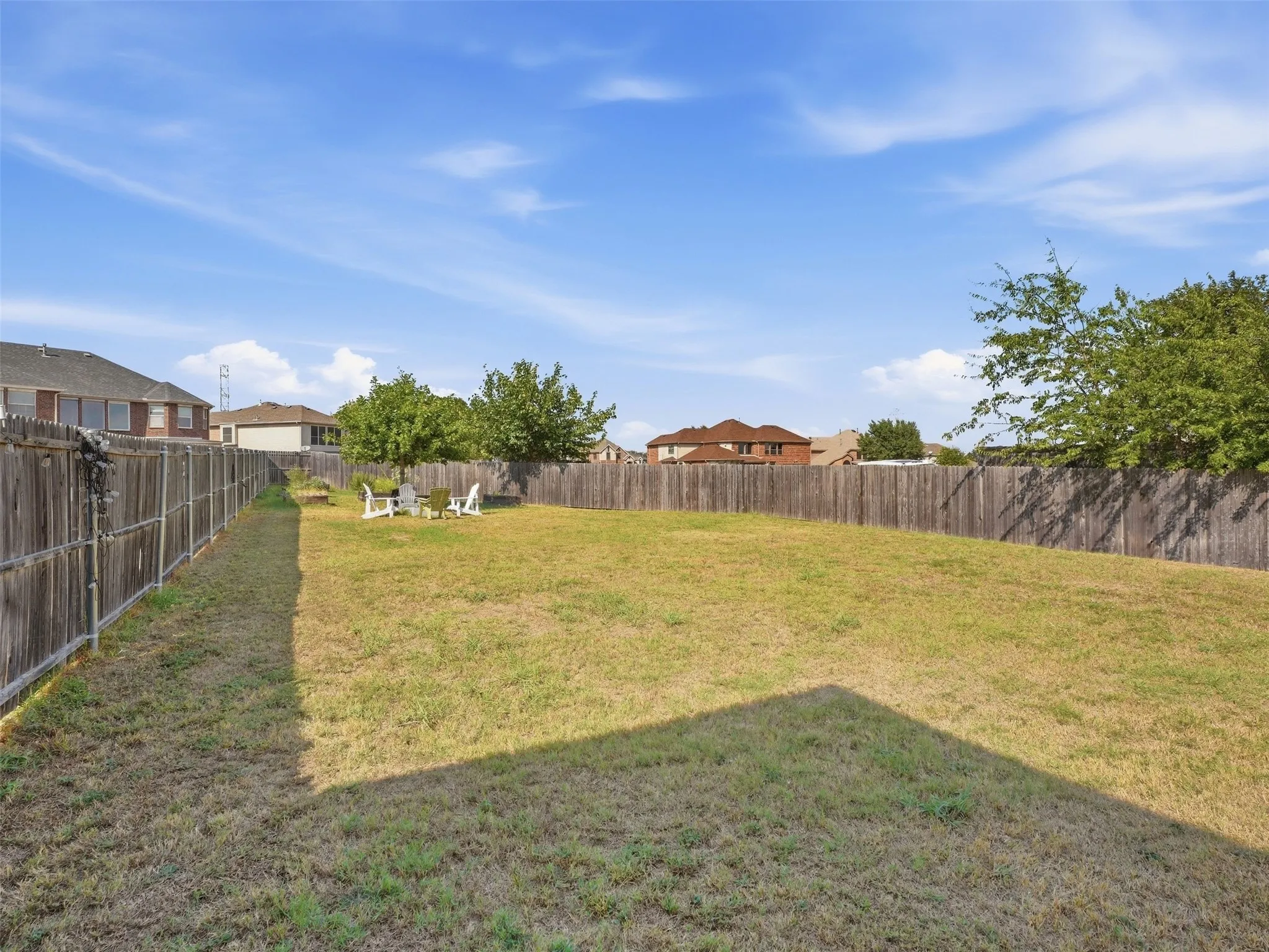 Expansive backyard featuring a wood fence perimeter and mature trees
