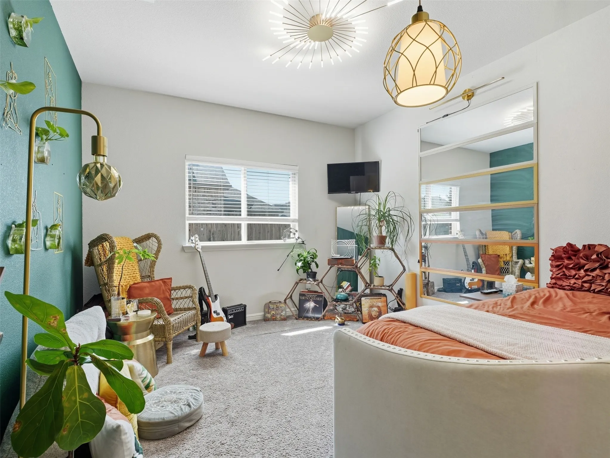 Carpeted bedroom featuring a large window, a built-in wall mirror, and two distinct ceiling light fixtures