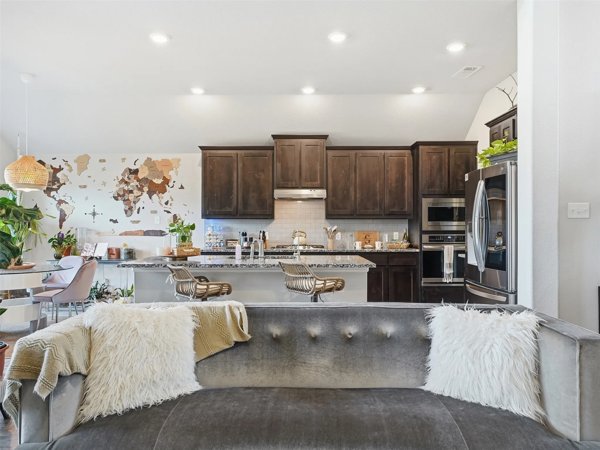 Kitchen featuring dark wood-finish cabinetry, stainless steel appliances, a tile backsplash, and an island with a light-toned countertop