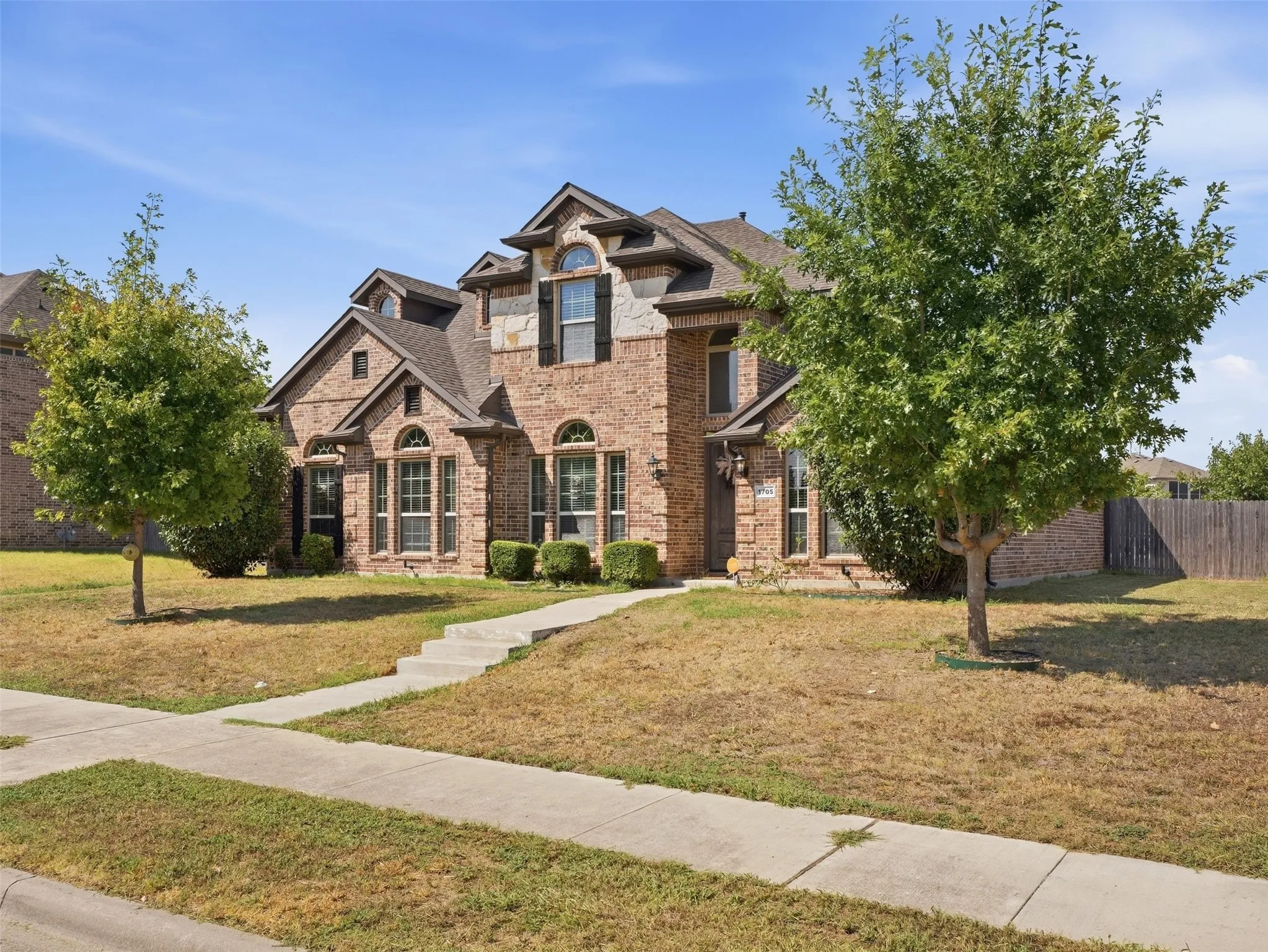Brick facade with stone accents, arched windows, and dark shutters