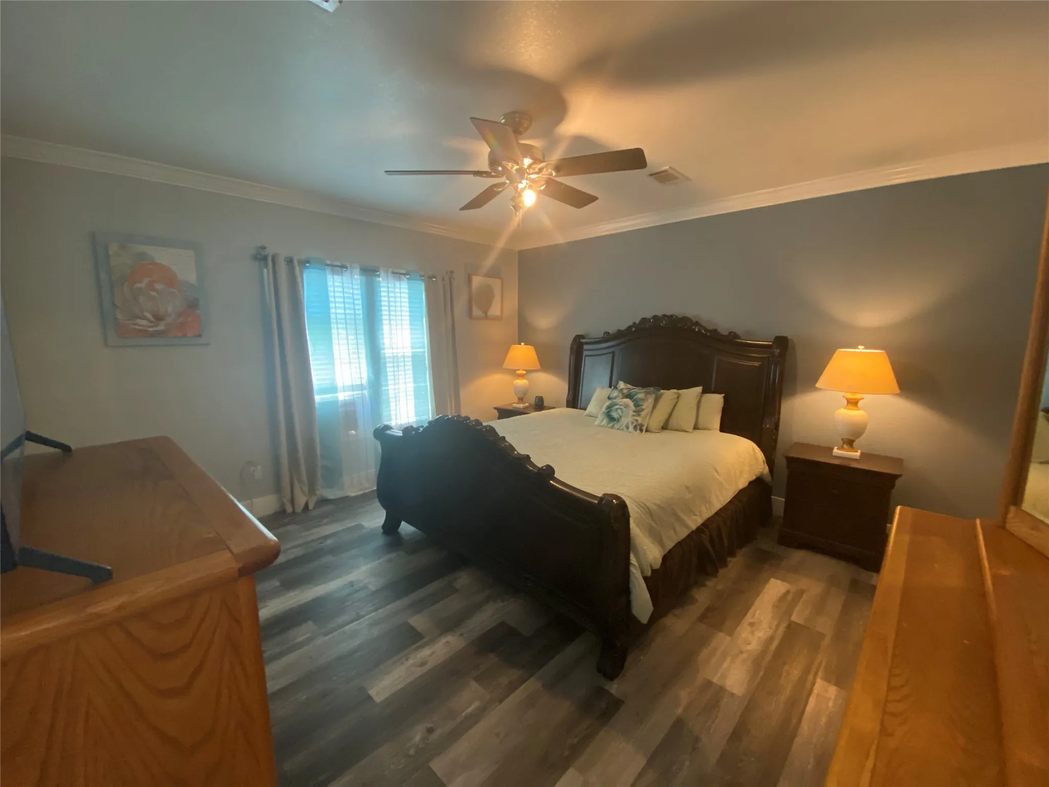 Bedroom with crown molding, dark wood finished floors, and ceiling fan