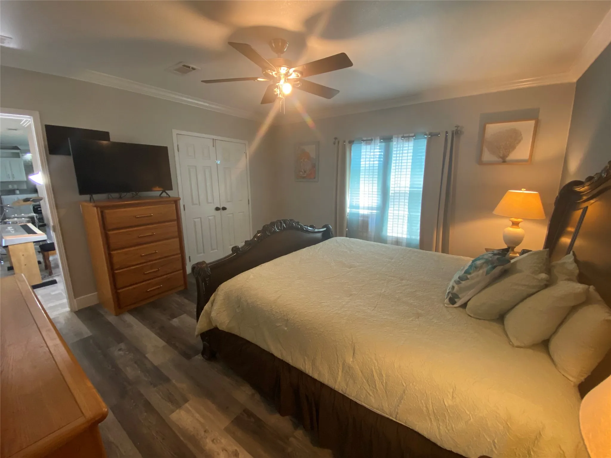 Bedroom featuring ornamental molding, dark wood-type flooring, a ceiling fan, and a closet