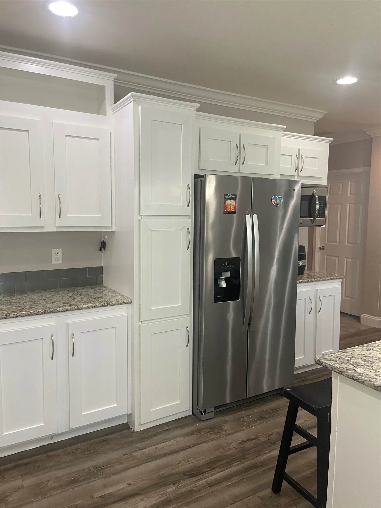 Kitchen featuring recessed lighting, white cabinets, appliances with stainless steel finishes, crown molding, and dark wood-style floors