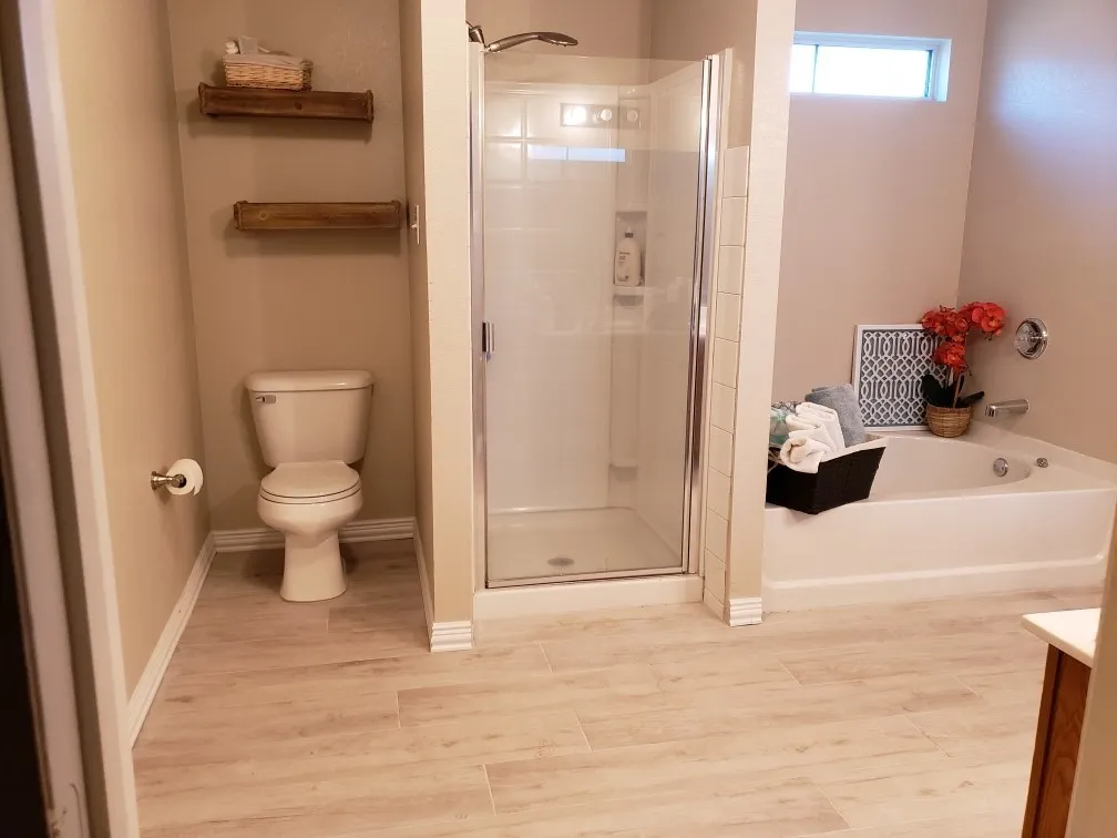 Walk-in shower with glass enclosure, soaking tub, and plank-style flooring