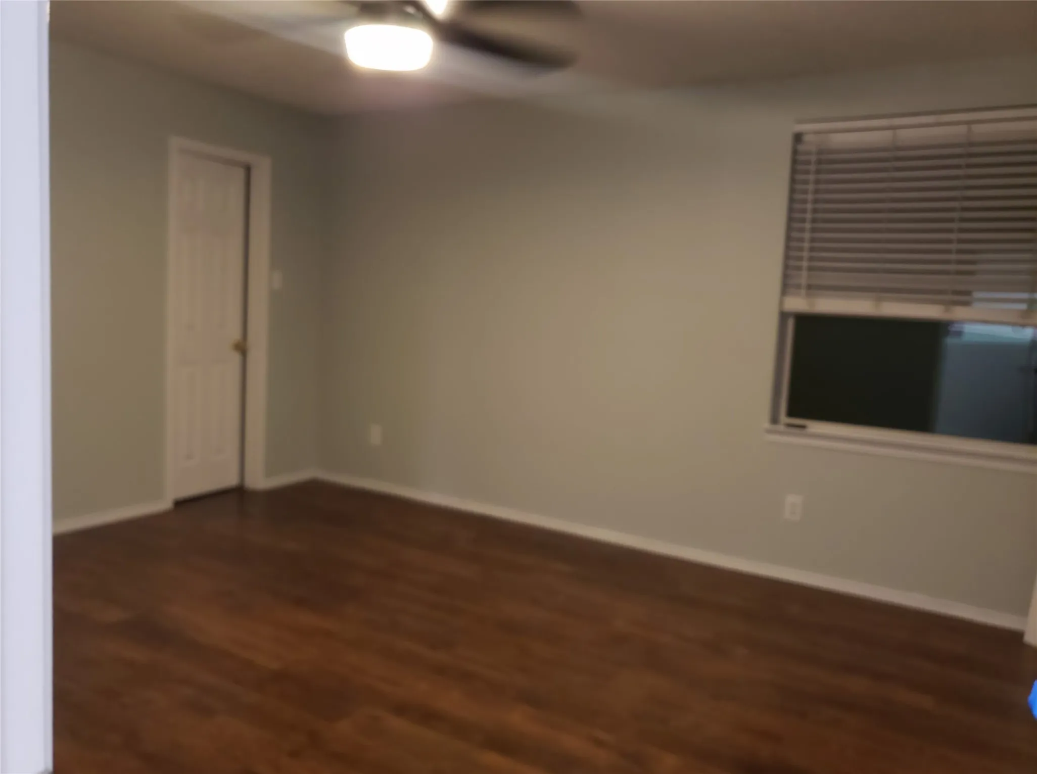 Wood-finish flooring, ceiling fan with integrated lighting, window with blinds, and painted walls