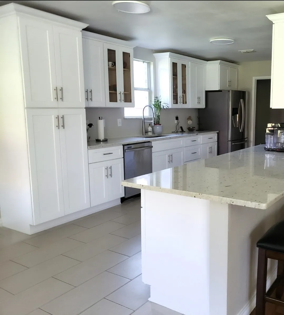 White shaker cabinetry with brushed nickel hardware, light-toned countertops, stainless steel appliances, and tile flooring
