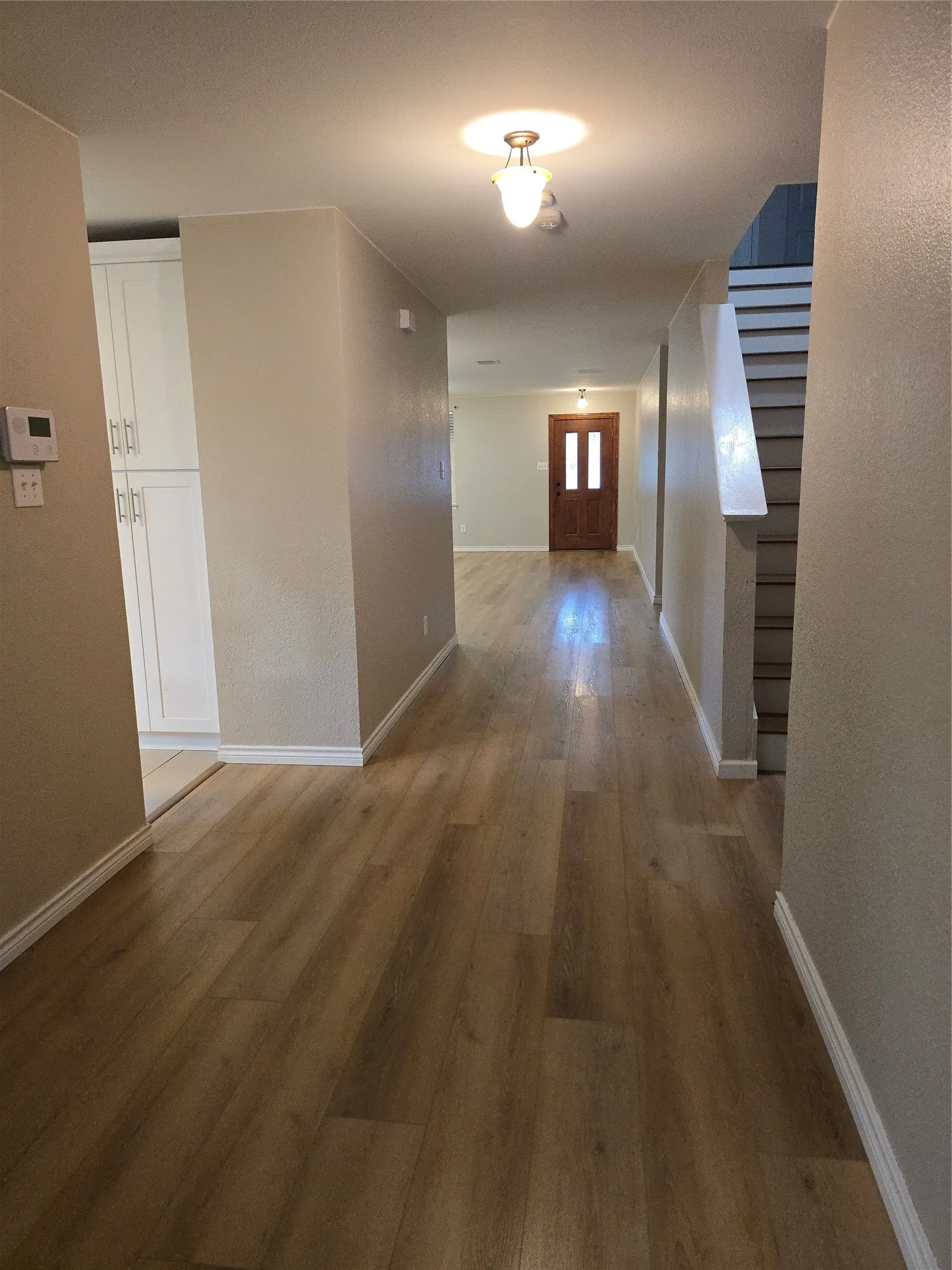 Wood-finish flooring throughout, bright recessed lighting, and a prominent staircase