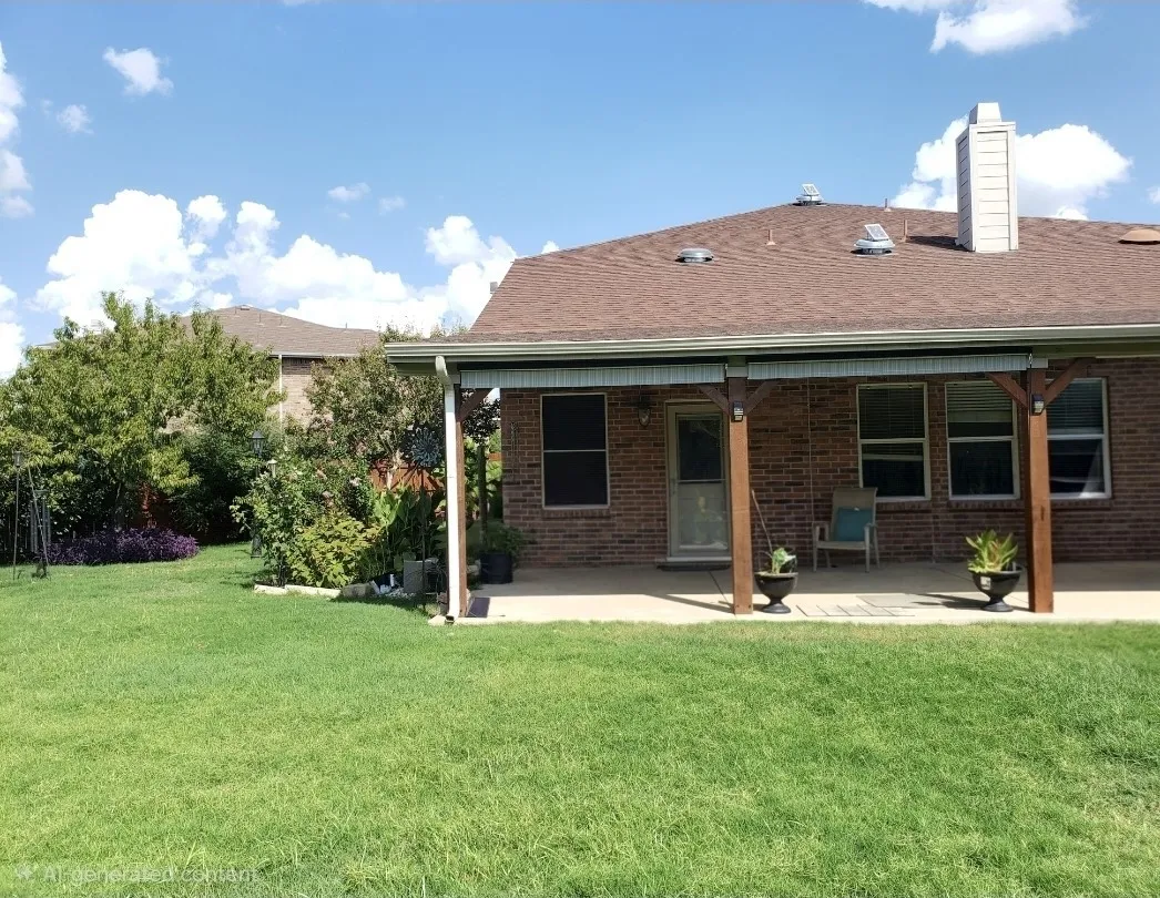 Expansive grassy yard with a covered patio featuring wood support columns, brick exterior, and a shingled roof