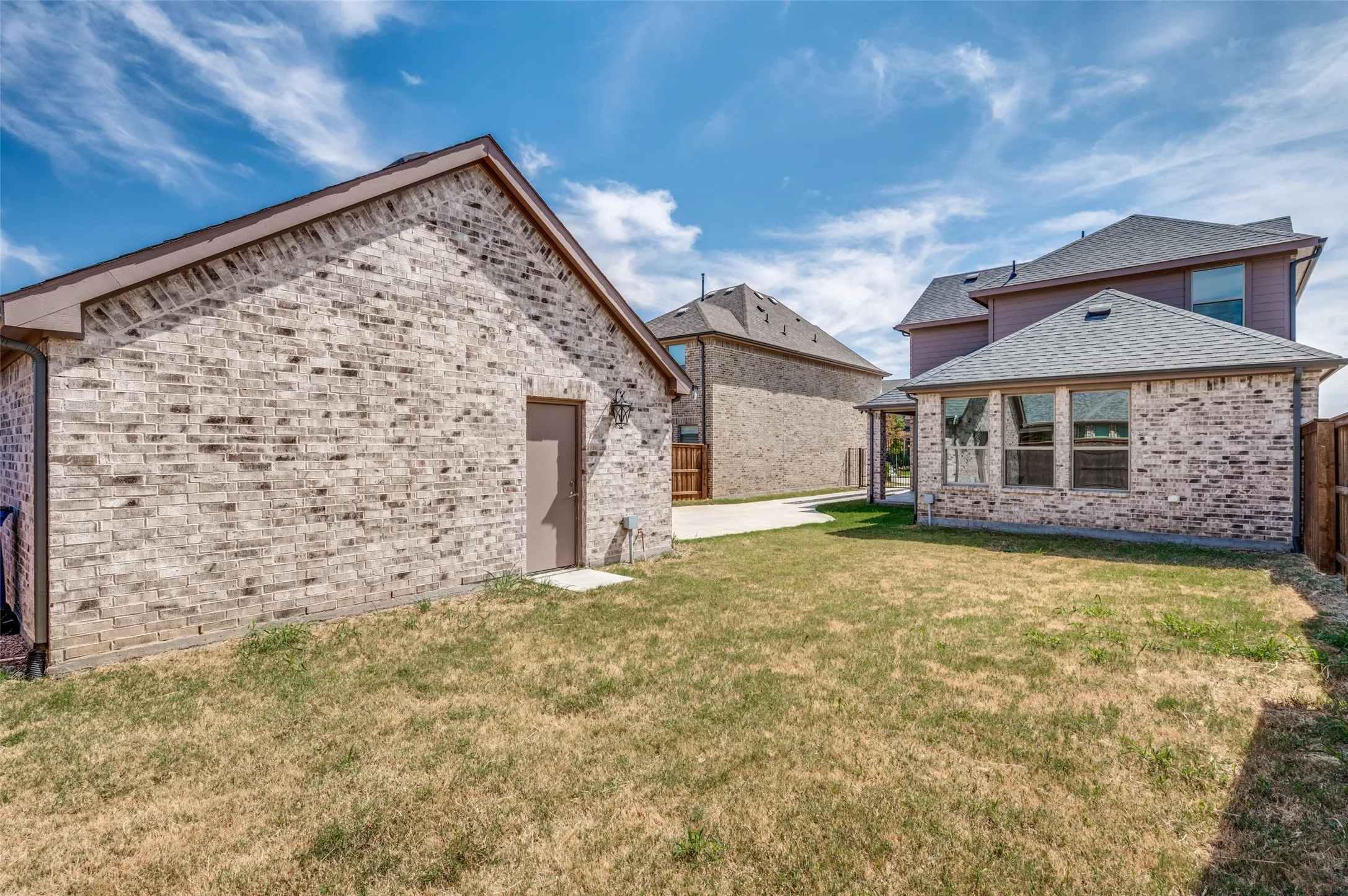 Exterior brick construction with contrasting roof lines, multiple windows, and a privacy fence