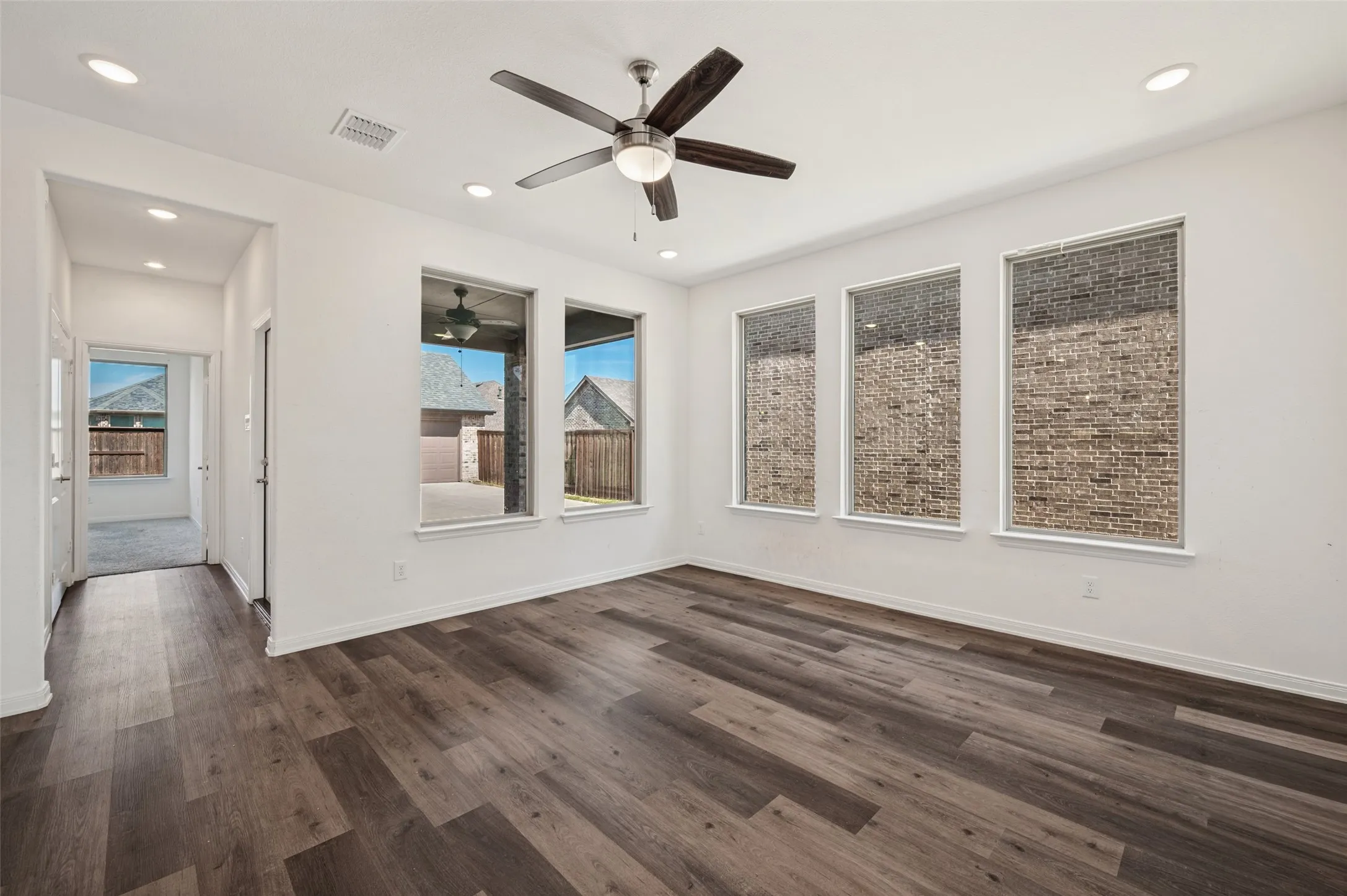 Spacious room with wood-finish flooring, recessed lighting, and a ceiling fan