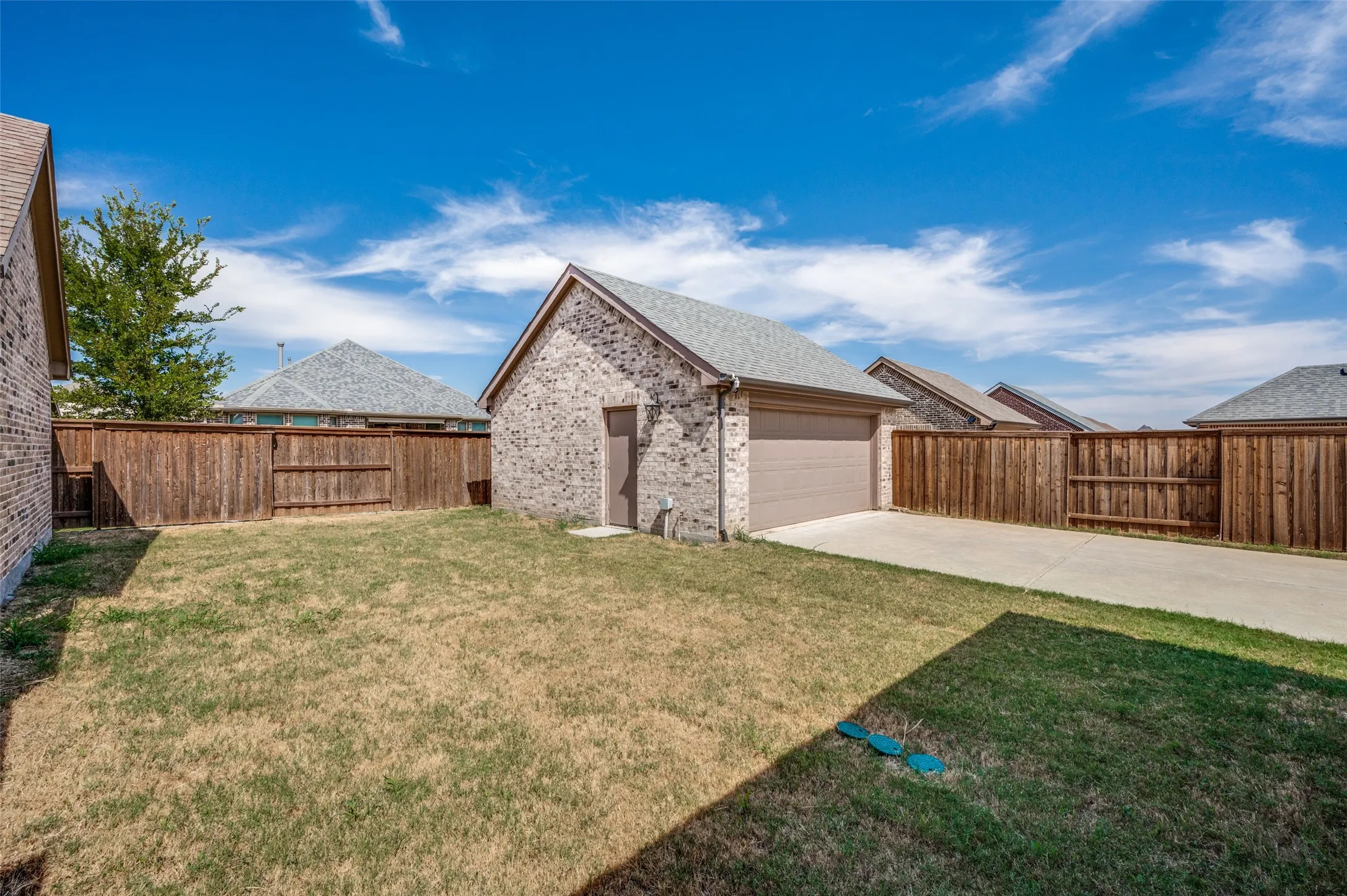 Detached brick garage with an automatic door, concrete driveway, and a private wooden fence