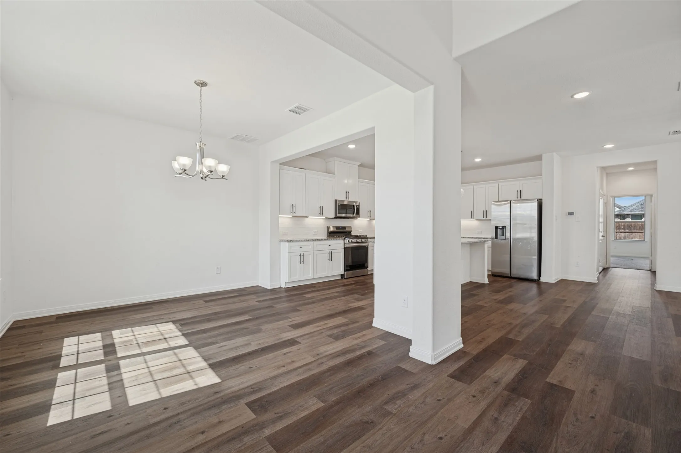 Wood-finish flooring throughout, recessed lighting, and a modern chandelier