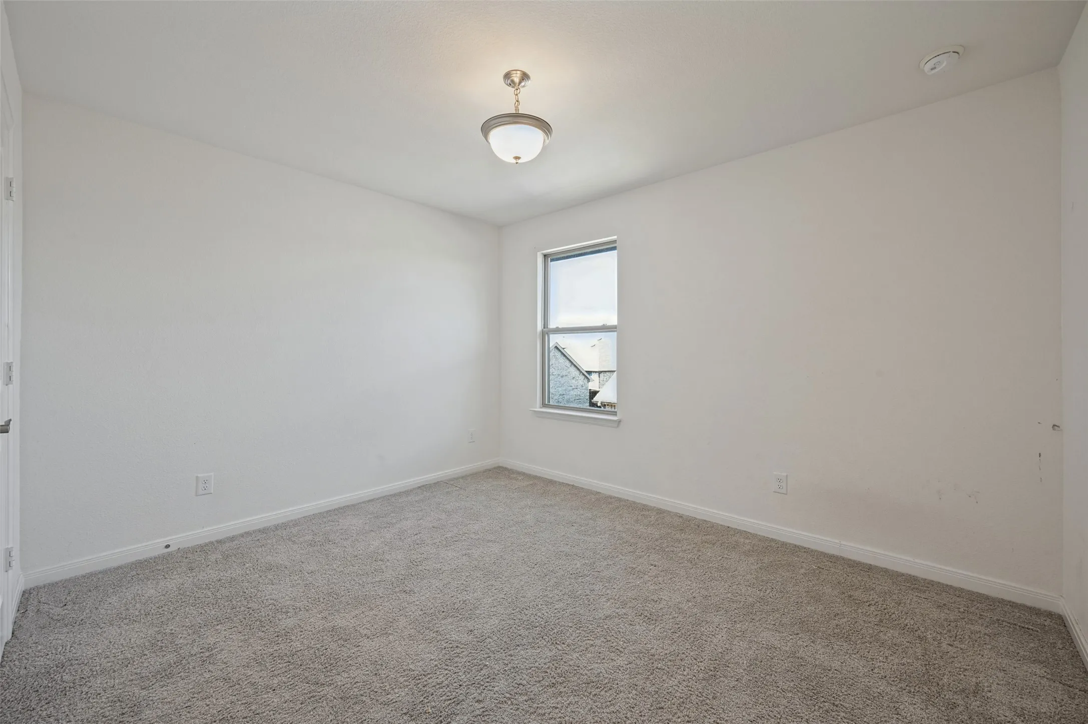Neutral-toned carpeting, single window with white trim, flush mount ceiling light fixture, and white painted walls