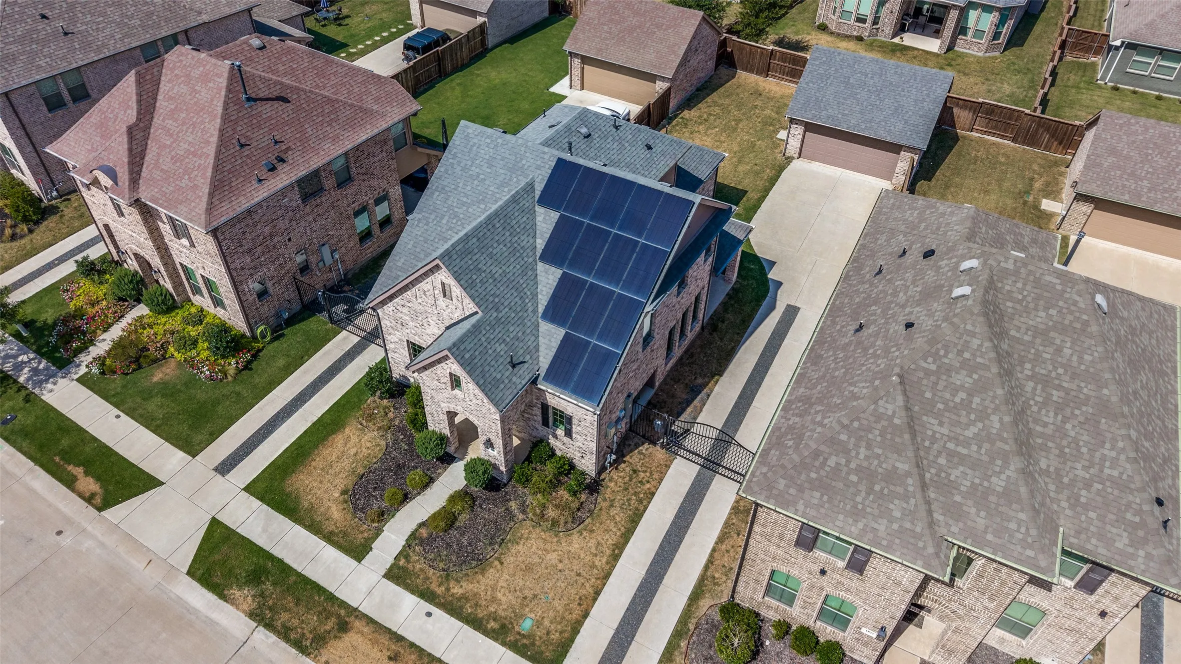 Brick exterior with solar panels, an attached garage, and a landscaped front yard