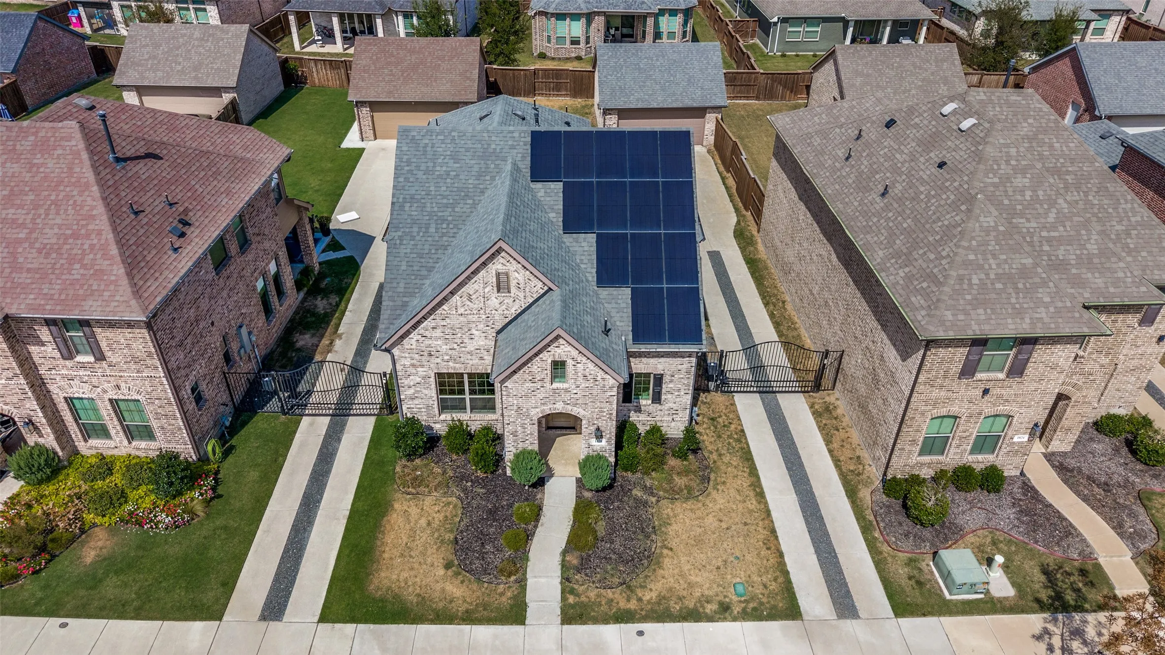 Brick exterior with gabled roof, solar panel array, arched entryway, and landscaped front yard
