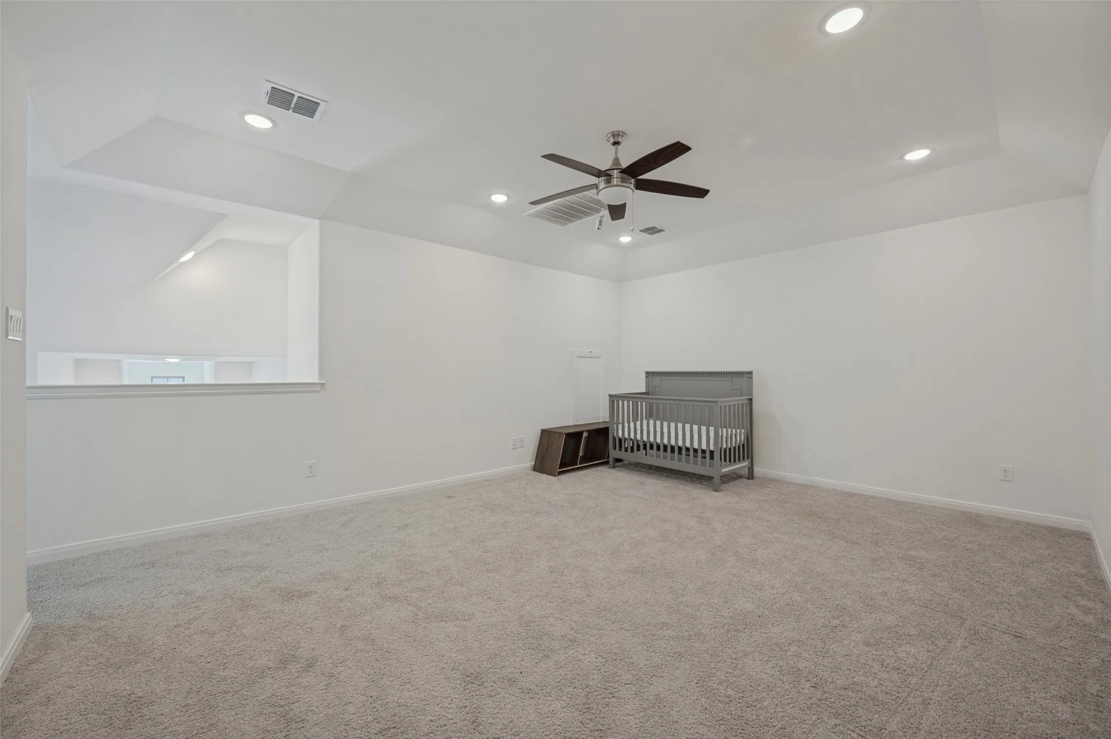 Spacious room featuring vaulted ceilings, recessed lighting, a ceiling fan, and plush carpeting