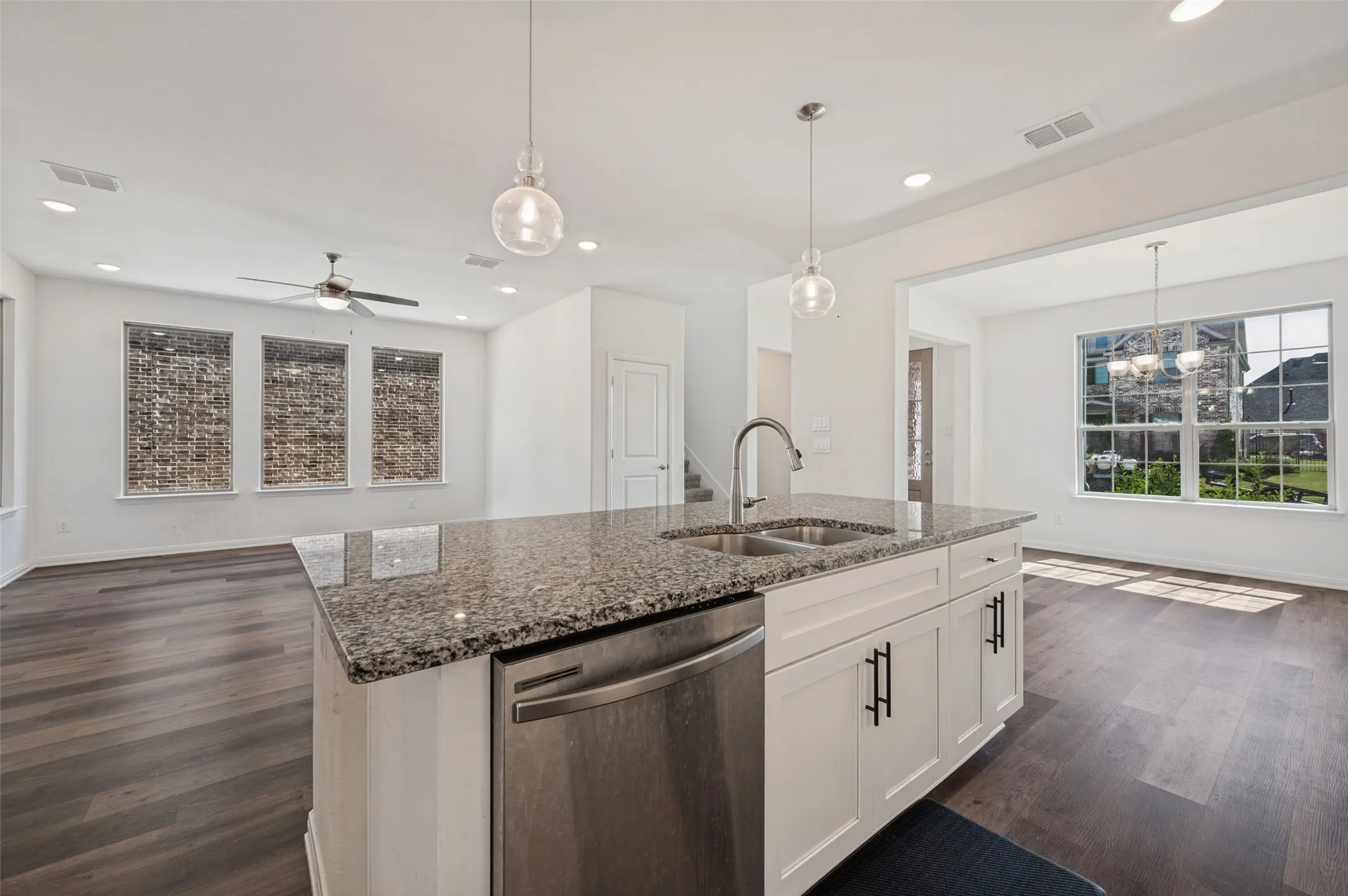 Kitchen island with granite countertop, double basin sink, and stainless steel dishwasher