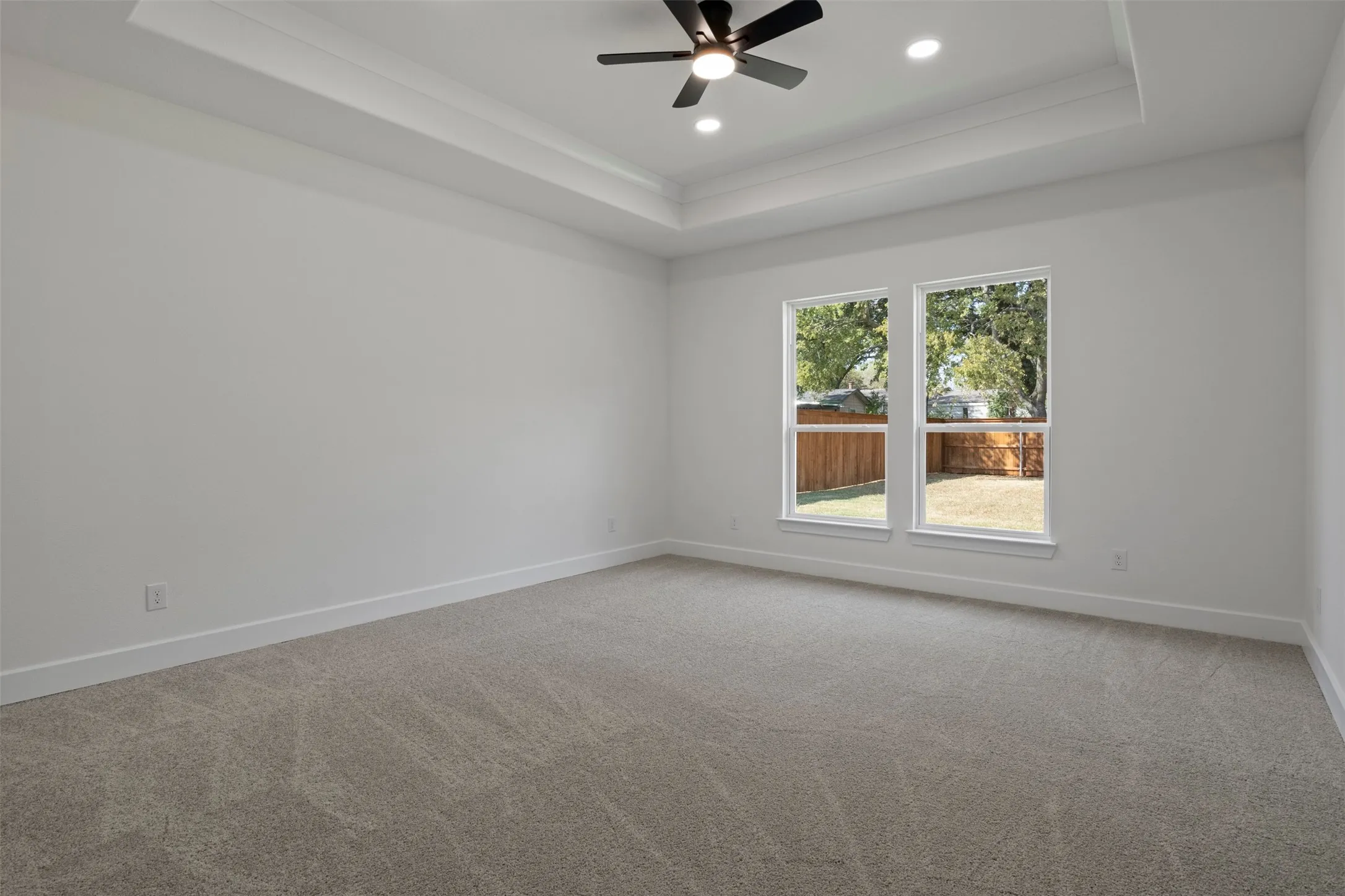 Spacious room featuring a tray ceiling, recessed lighting, and a ceiling fan