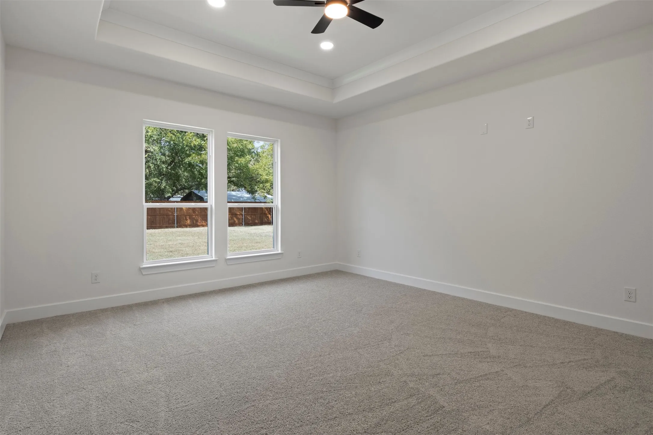 Recessed lighting and ceiling fan complement a tray ceiling
