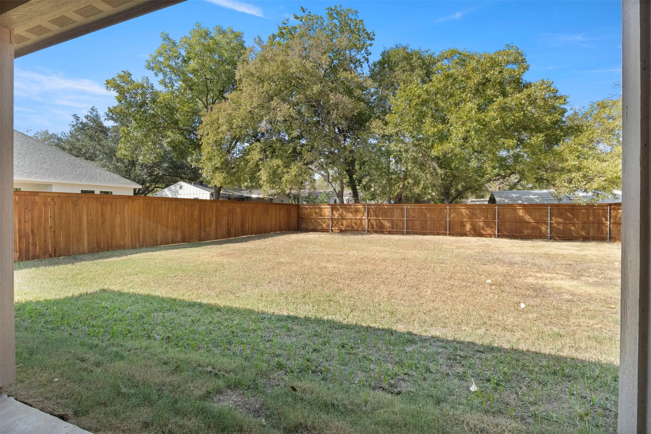 Expansive grass area with a surrounding wood fence and mature trees