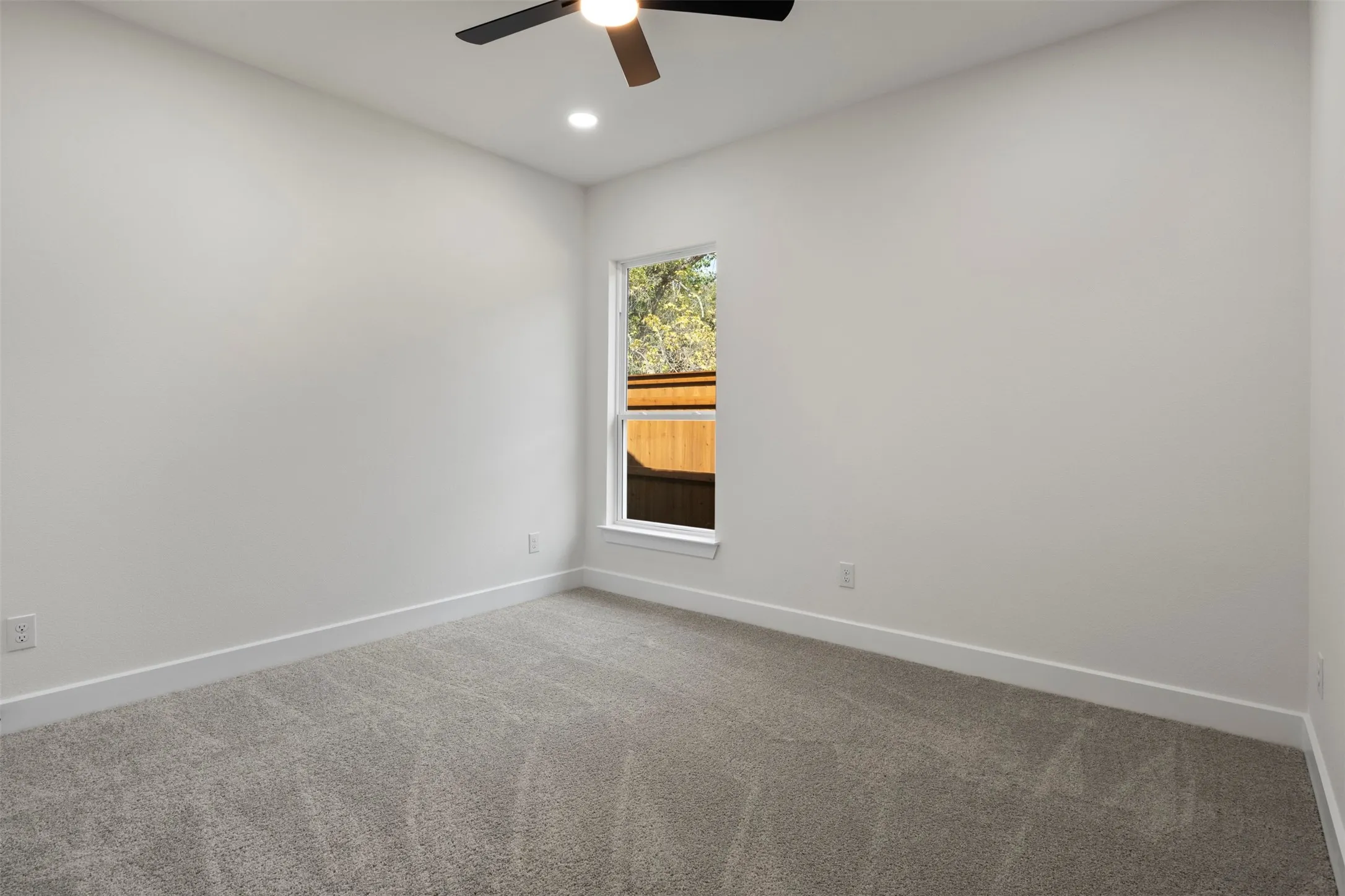Recessed ceiling lighting, ceiling fan fixture, single window, and neutral carpeting