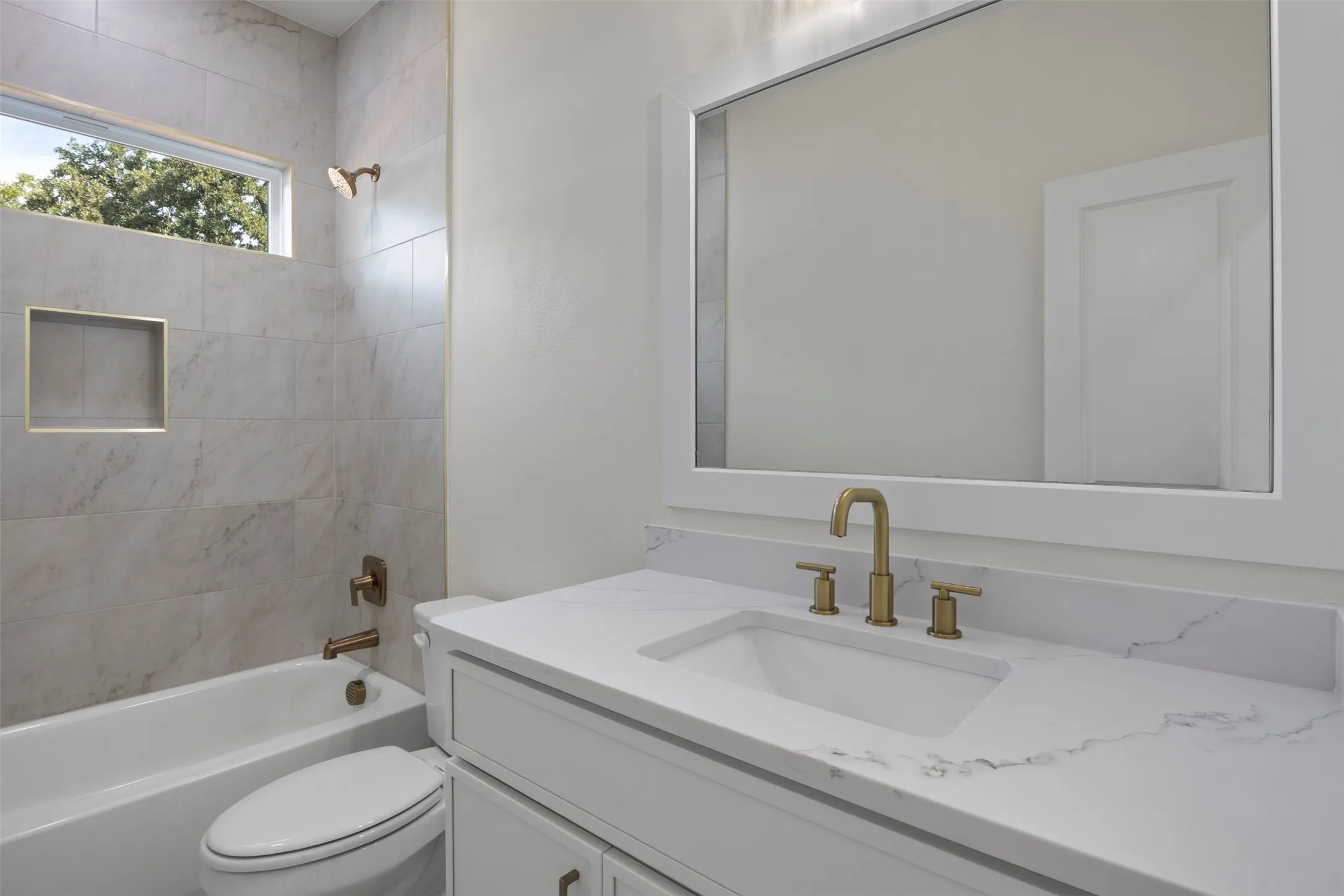 White vanity with a rectangular undermount sink, a stone-finish countertop, and gold-tone fixtures