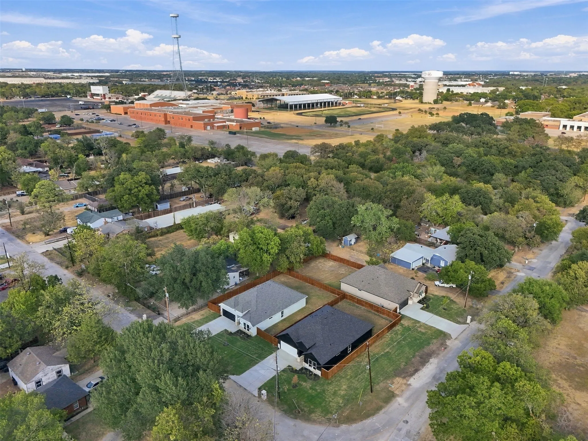 Aerial depiction of properties with surrounding mature trees and residential structures