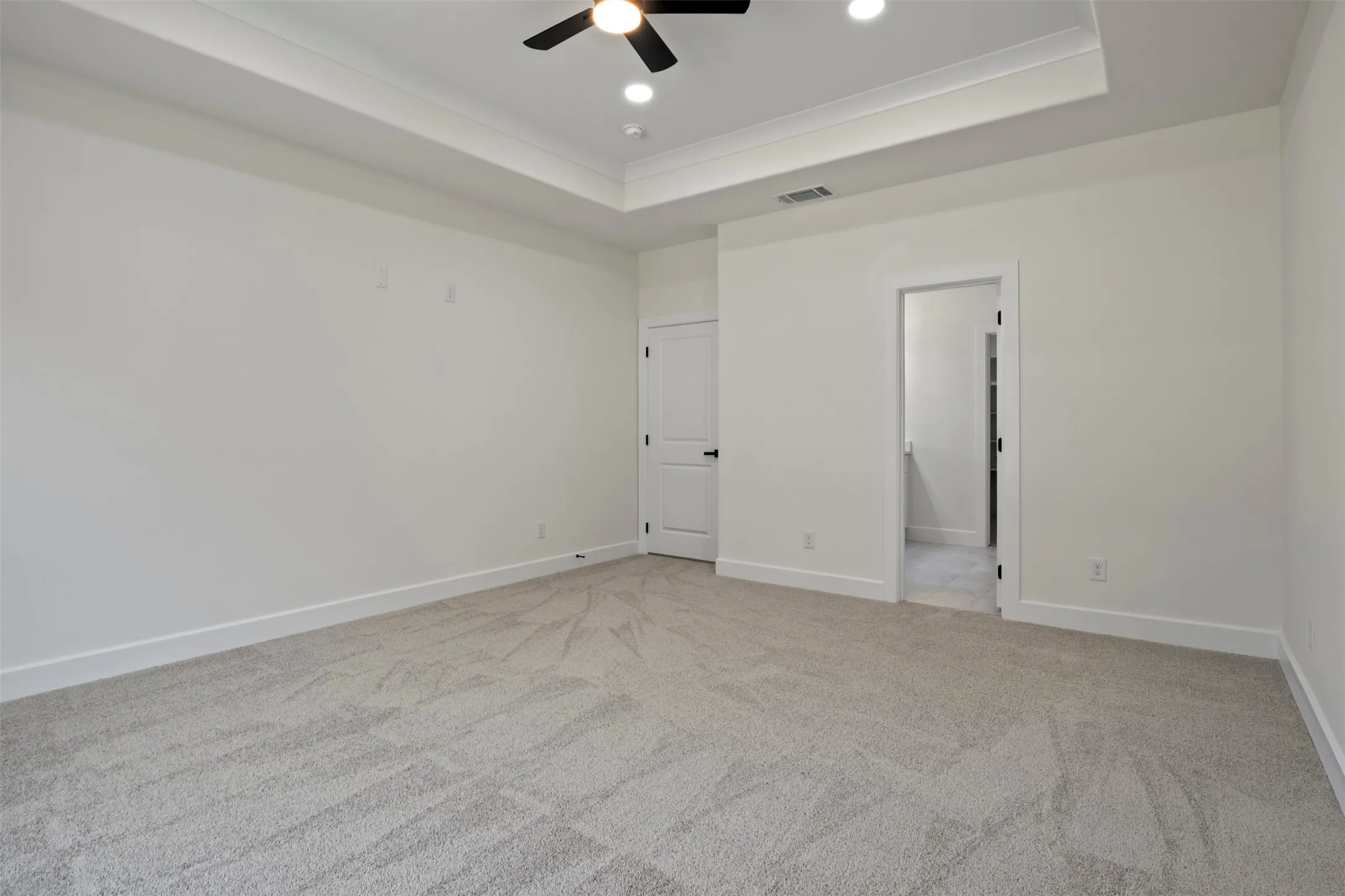 Spacious room with tray ceiling, recessed lighting, ceiling fan, carpet flooring, and white trim