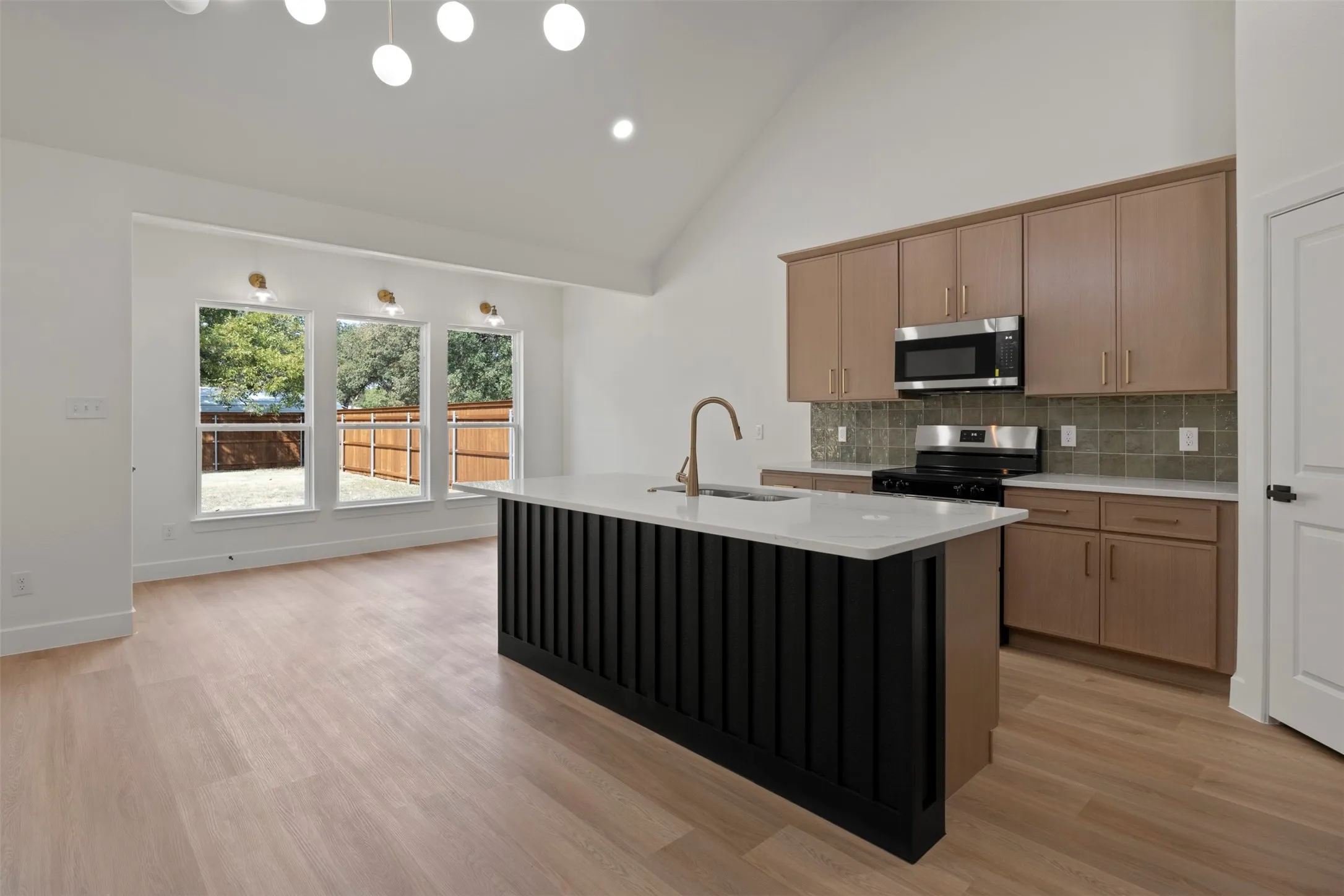 Open-concept living space featuring wood-finish flooring, a kitchen island with a white countertop, and stainless steel appliances