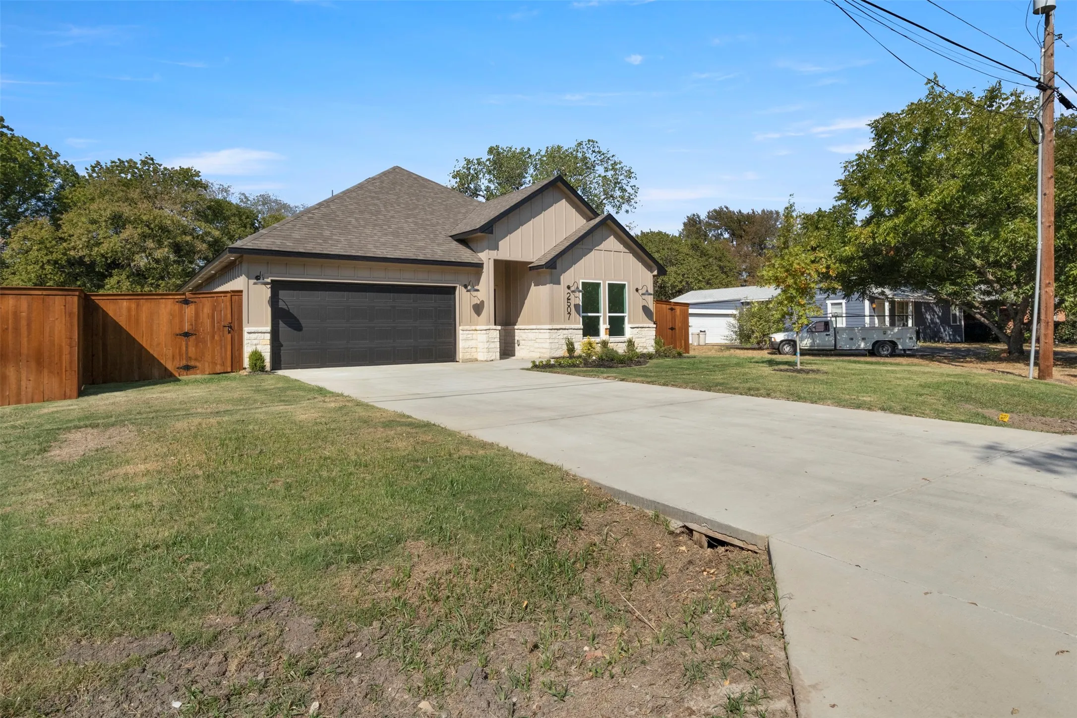 Single-story residence featuring a two-car garage, wood privacy fence, and concrete driveway