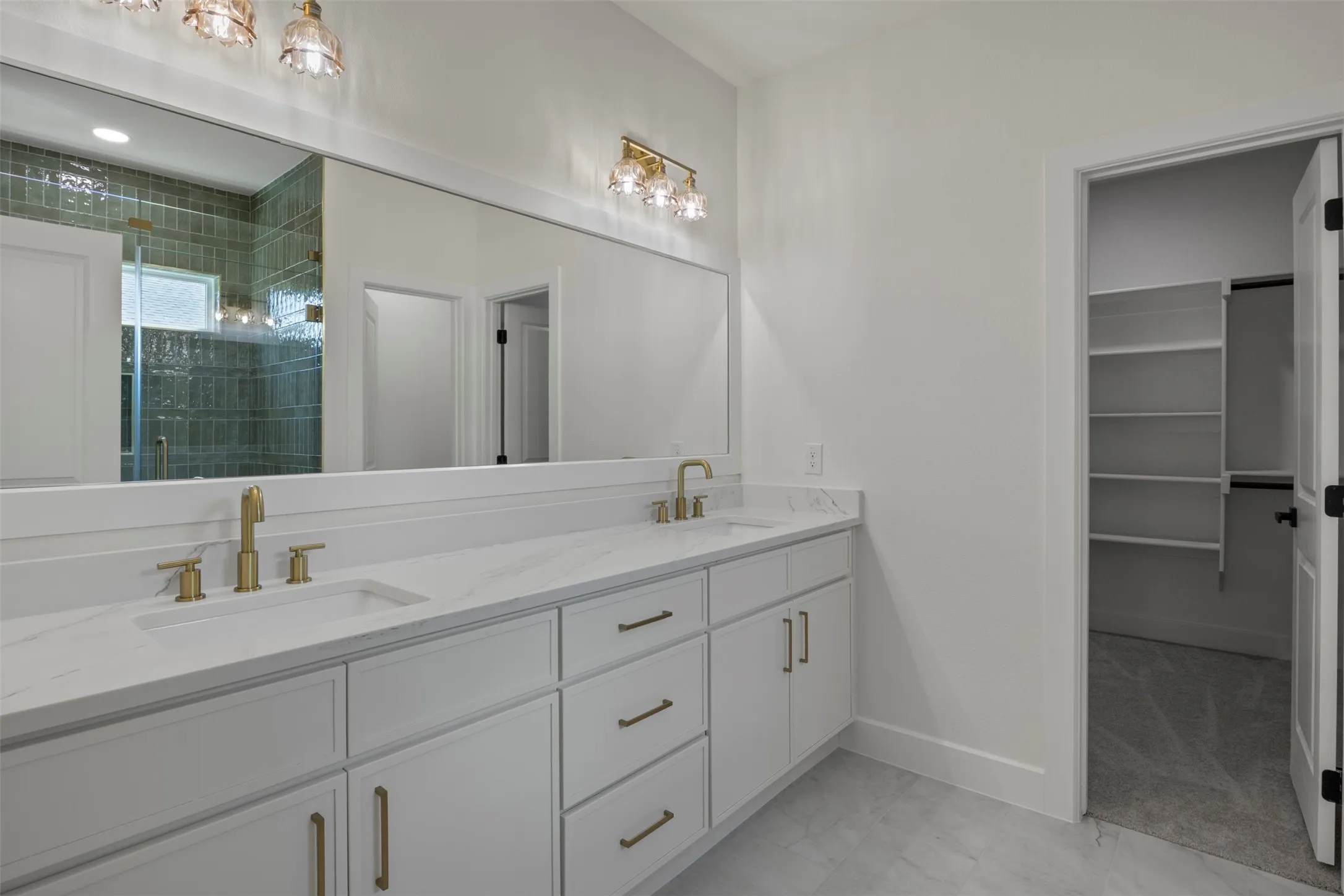 Dual vanity with white cabinetry, gold-finish fixtures, and a white countertop