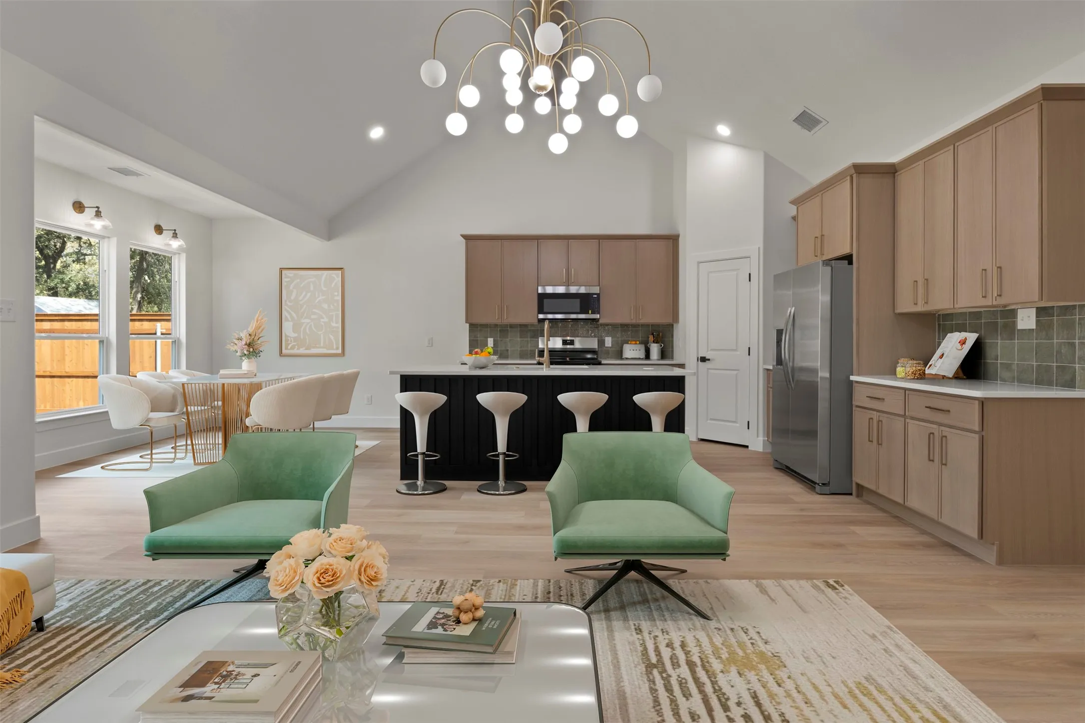Vaulted ceilings with a statement chandelier, wood-finish flooring, two-tone kitchen cabinetry, an integrated kitchen island, and stainless steel appliances