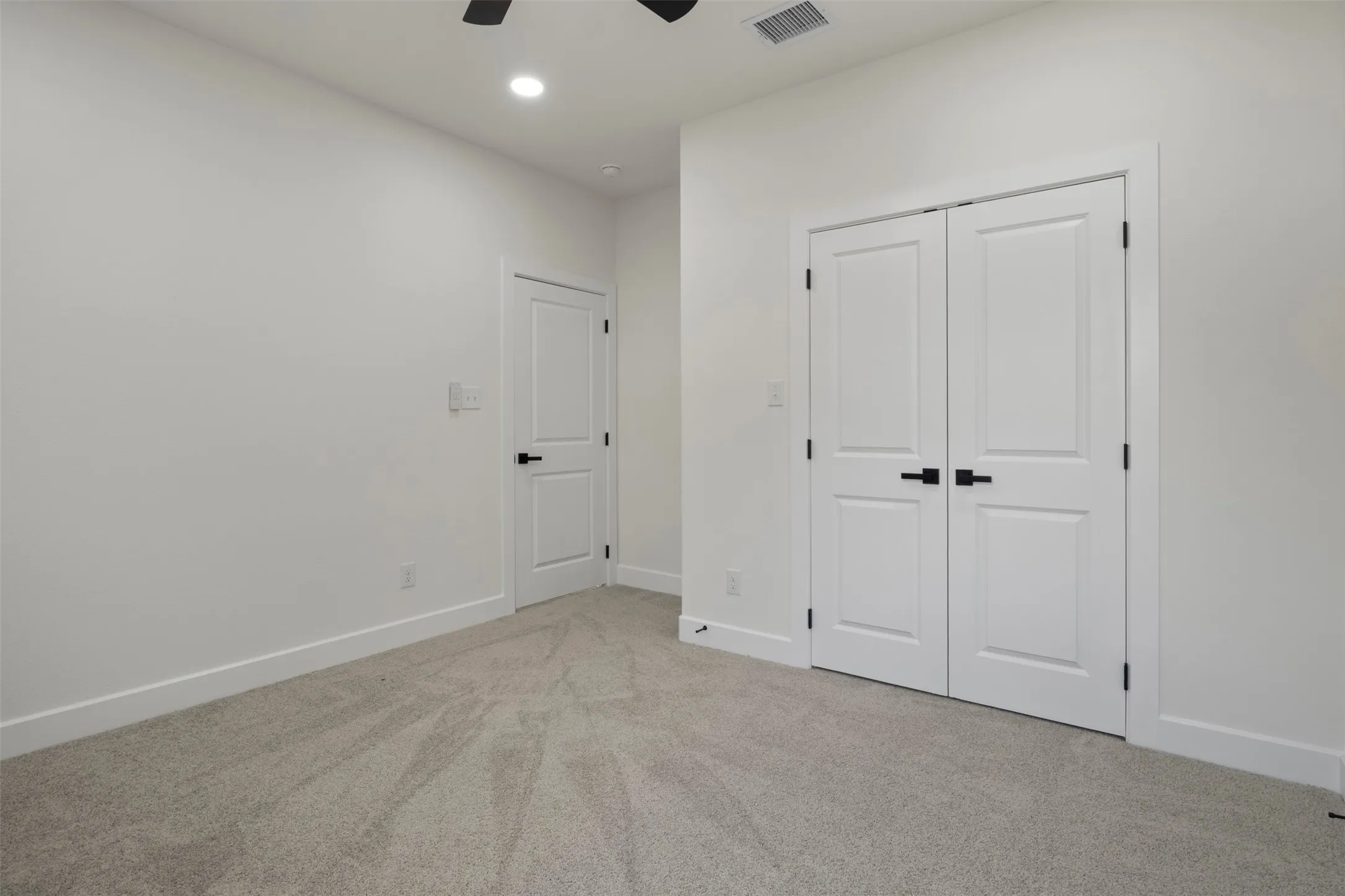 Recessed lighting, plush carpet flooring, white trim, flat-panel interior doors, and matte black hardware