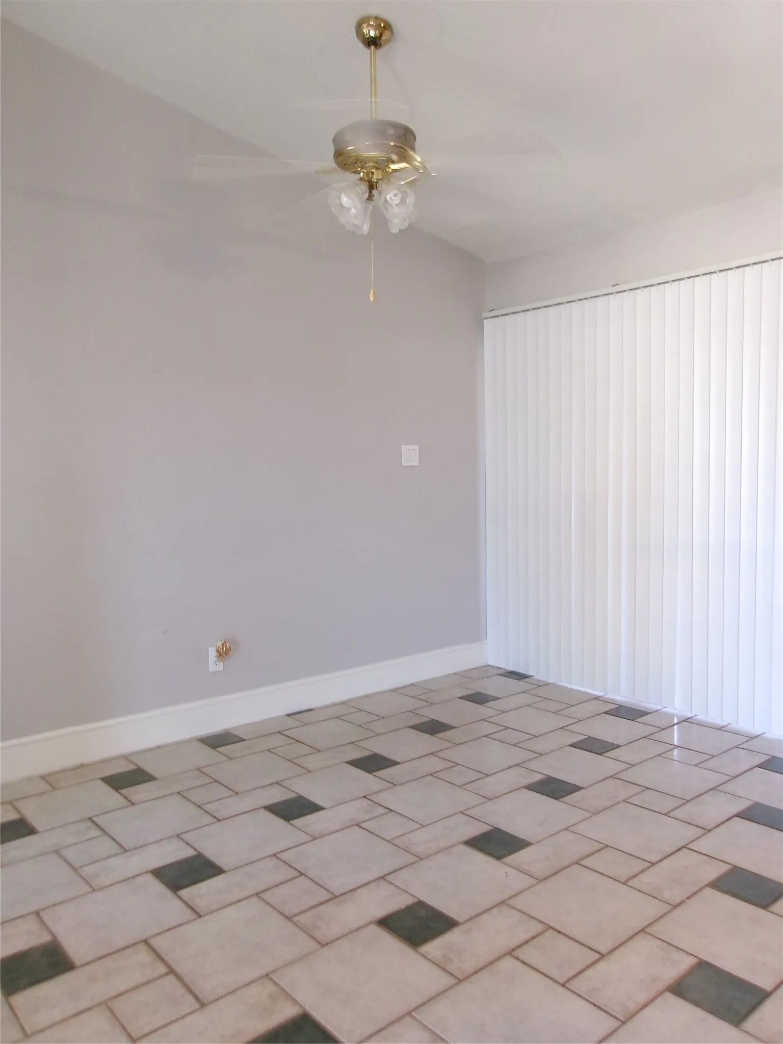 Patterned tile flooring, ceiling fan with integrated lighting, and vertical window blinds