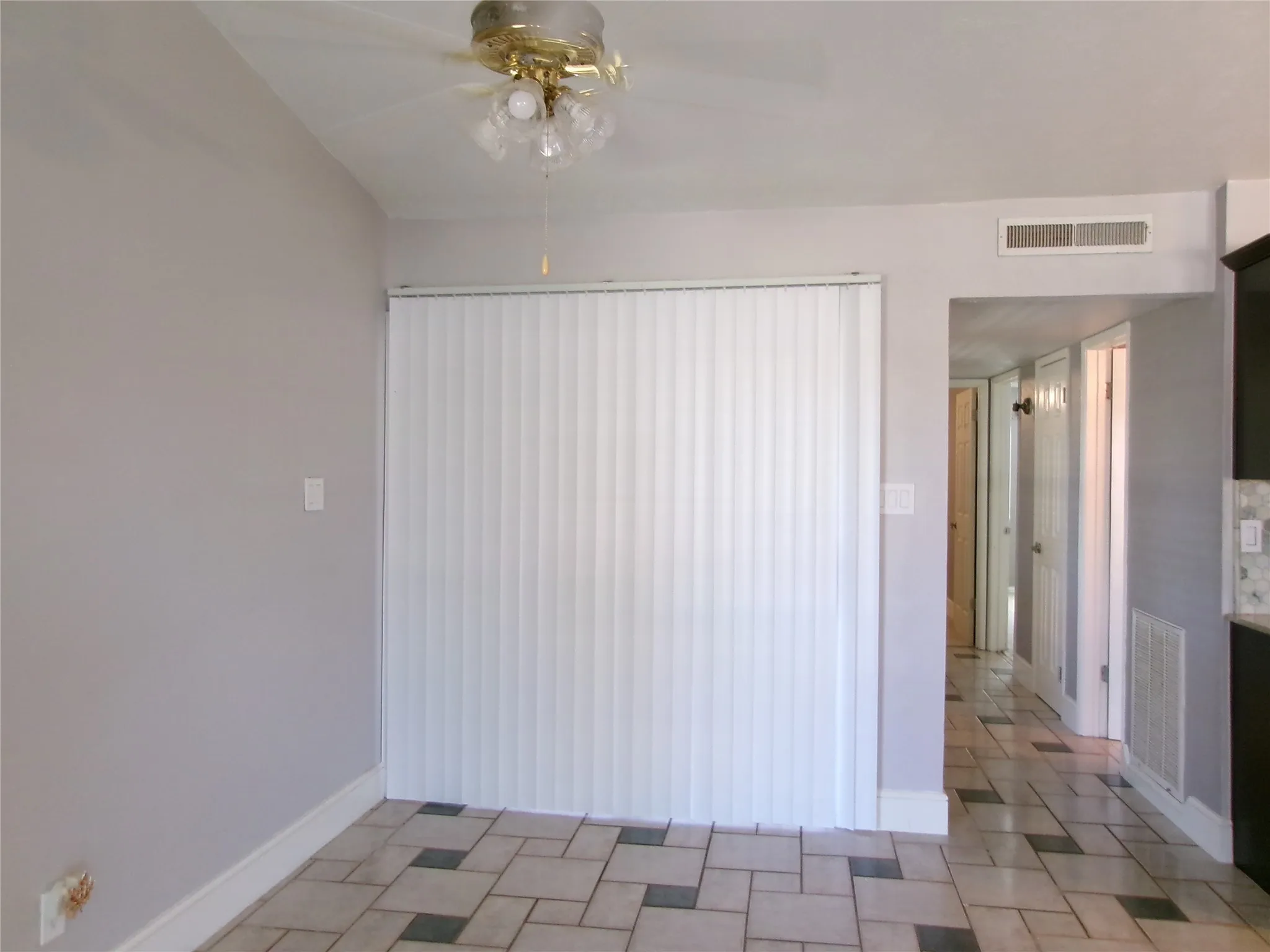 Ceiling fan with integrated lighting, vertical blinds, light-toned wall paint, patterned tile flooring, and white trim