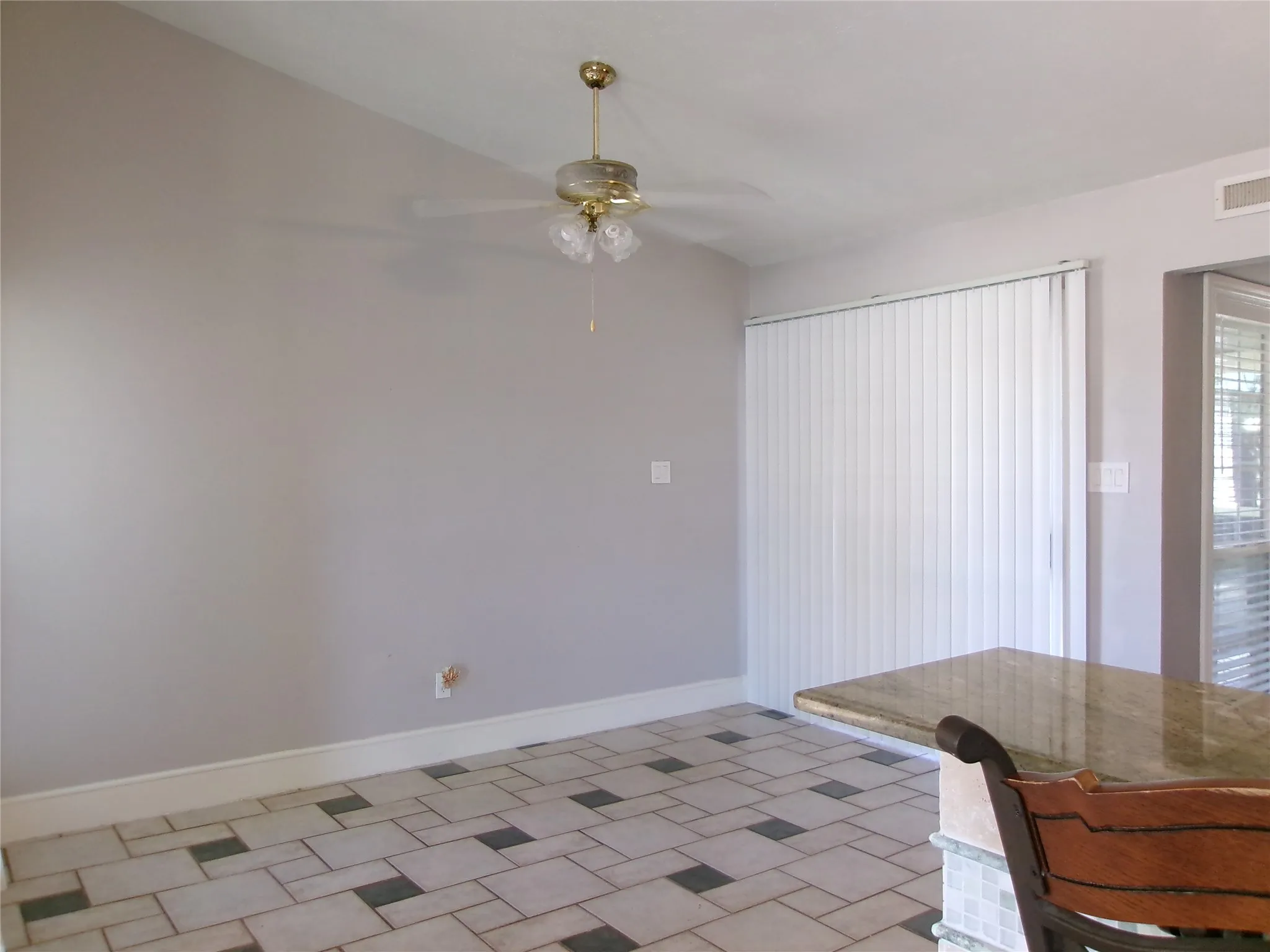 Ceramic tile flooring with a geometric pattern, ceiling fan with integrated lighting, vertical blinds, and a built-in countertop with a polished surface