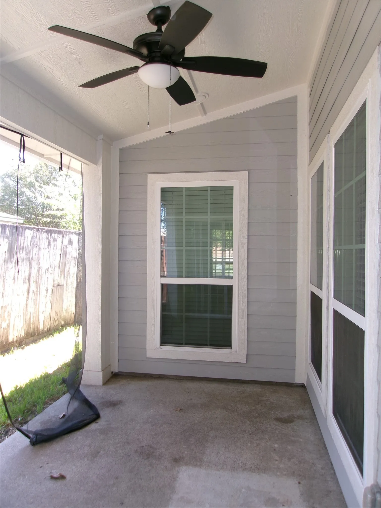 Covered patio featuring a ceiling fan, concrete flooring, and horizontal siding