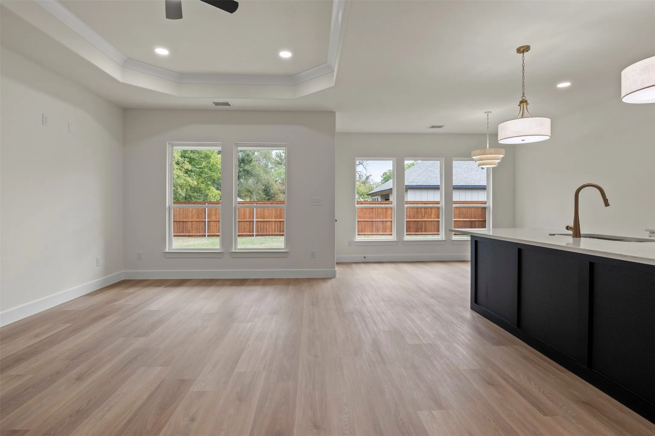 Wood-finish flooring throughout, featuring a kitchen island with a light-colored countertop and a bronze-toned faucet